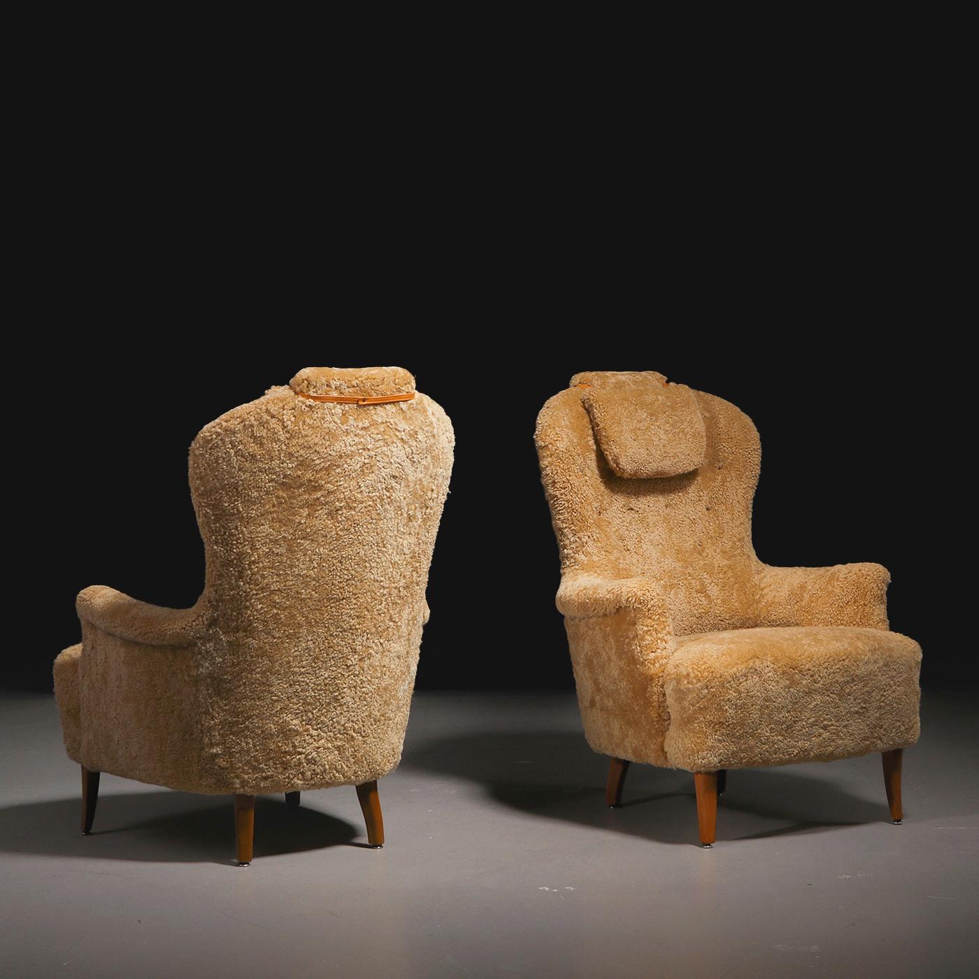 Pair of high-back Swedish armchairs (model 'Farmor'), designed by Swedish designer and architect Carl Malmsten. Manufactured by O.H. Sjögren in the 1950s. Wooden legs, armchairs reupholstered in Honey sheepskin.

The iconic 'Farmor' (or