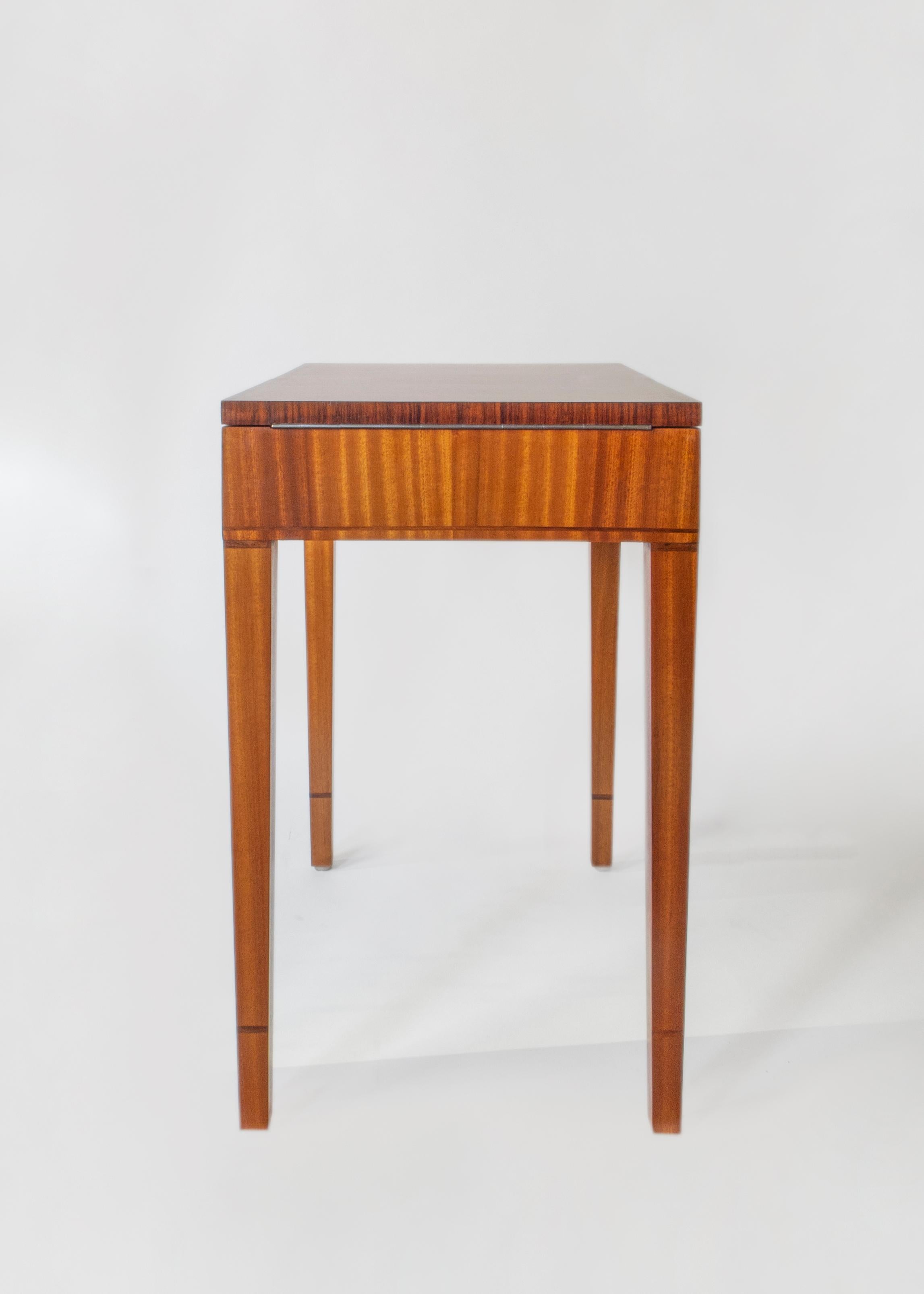 The bookmatched satinwood top, opening on piano hinges to reveal a removable tray divided into fourteen compartments, above a stylized foliate freeze executed in seared holly and boxwood marquetry, on four square tapering legs, with rosewood banding