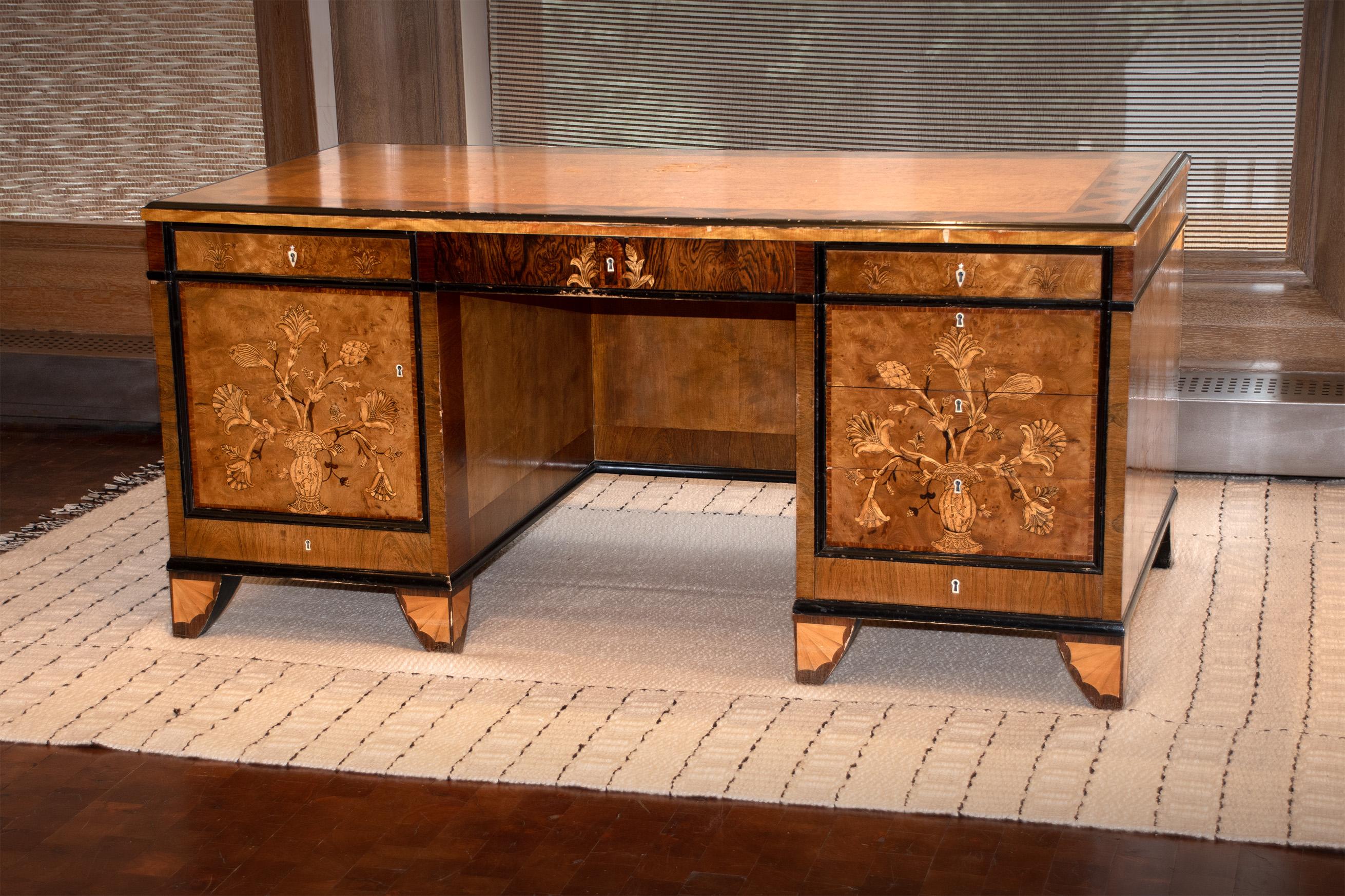 Veneered Pedestal Desk designed by Carl Malmsten (1923)

Desk includes floral motifs, a central frieze drawer, and twin pedestals (frieze drawers with veneered initials T.L). One opens to five sliding shelves, and the other to five drawers. The feet