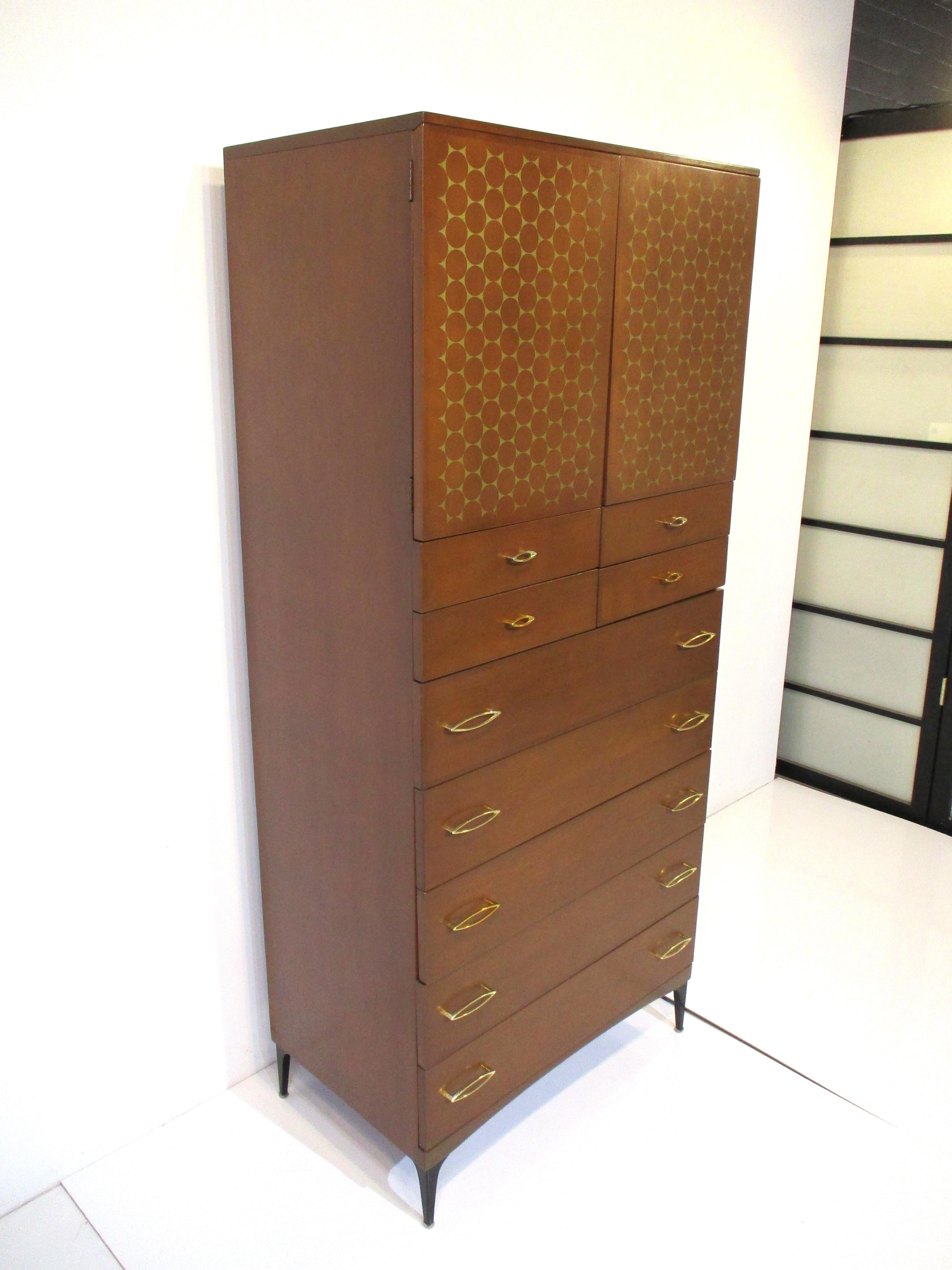 A stunning tall double semainer dresser chest with two upper push doors, inside one adjustable shelve and storage and the front face having gold imprinted designs. Below four smaller drawers and five larger drawer with cast gold toned handles giving