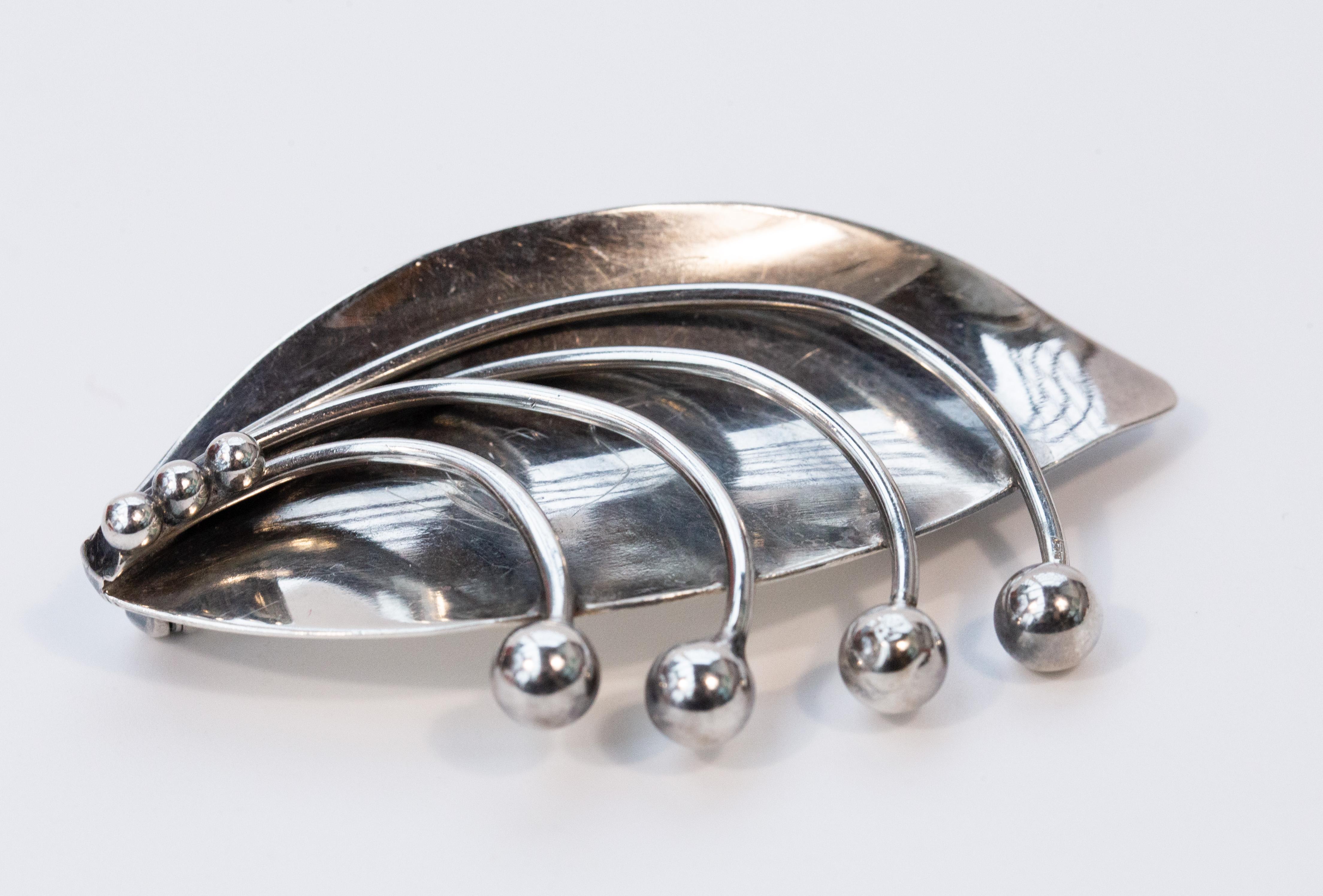 A vintage modernist solid silver sterling brooch designed by Carl Ove Frydensberg in Copenhagen, Denmark. The brooch features floral/foliage decoration and it is in very good vintage condition. The backside of the brooch is marked Sterling COF