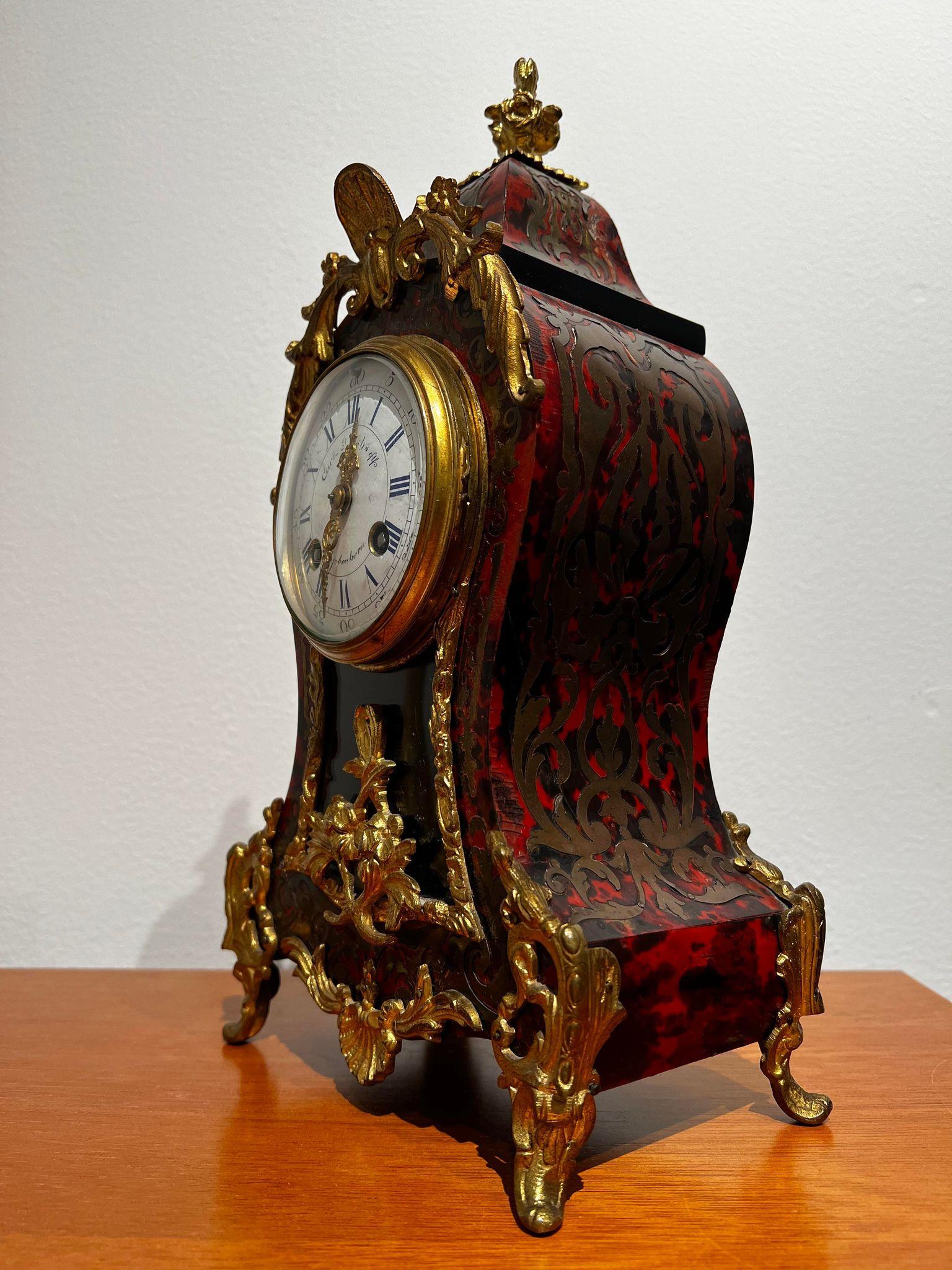 Carl Ranch's eff. Small antique mantel clock is a beautiful and unique clock that was made in France in the 1850s. The case is made in Rococo Rivival style with a inlaid tortoiseshell with brass, and the clock shows Roman and Arabic numerals. The