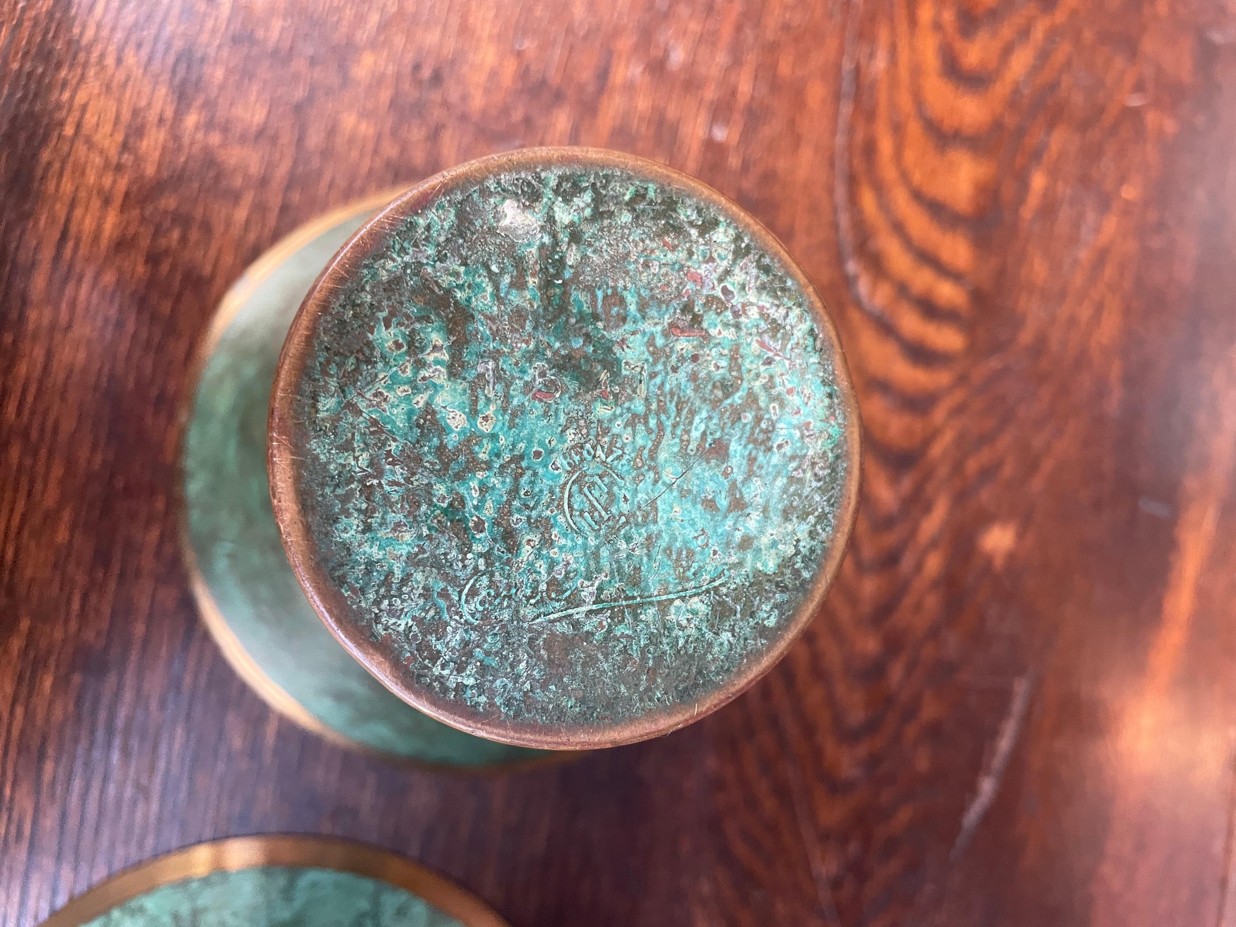 A striking pair of early 20th-century bronze vases by noted American metalsmith Carl Sorensen, each showcasing his signature rich hand-applied verdigris patina and finely incised gilt bronze banding. The flared trumpet forms highlight the subtle