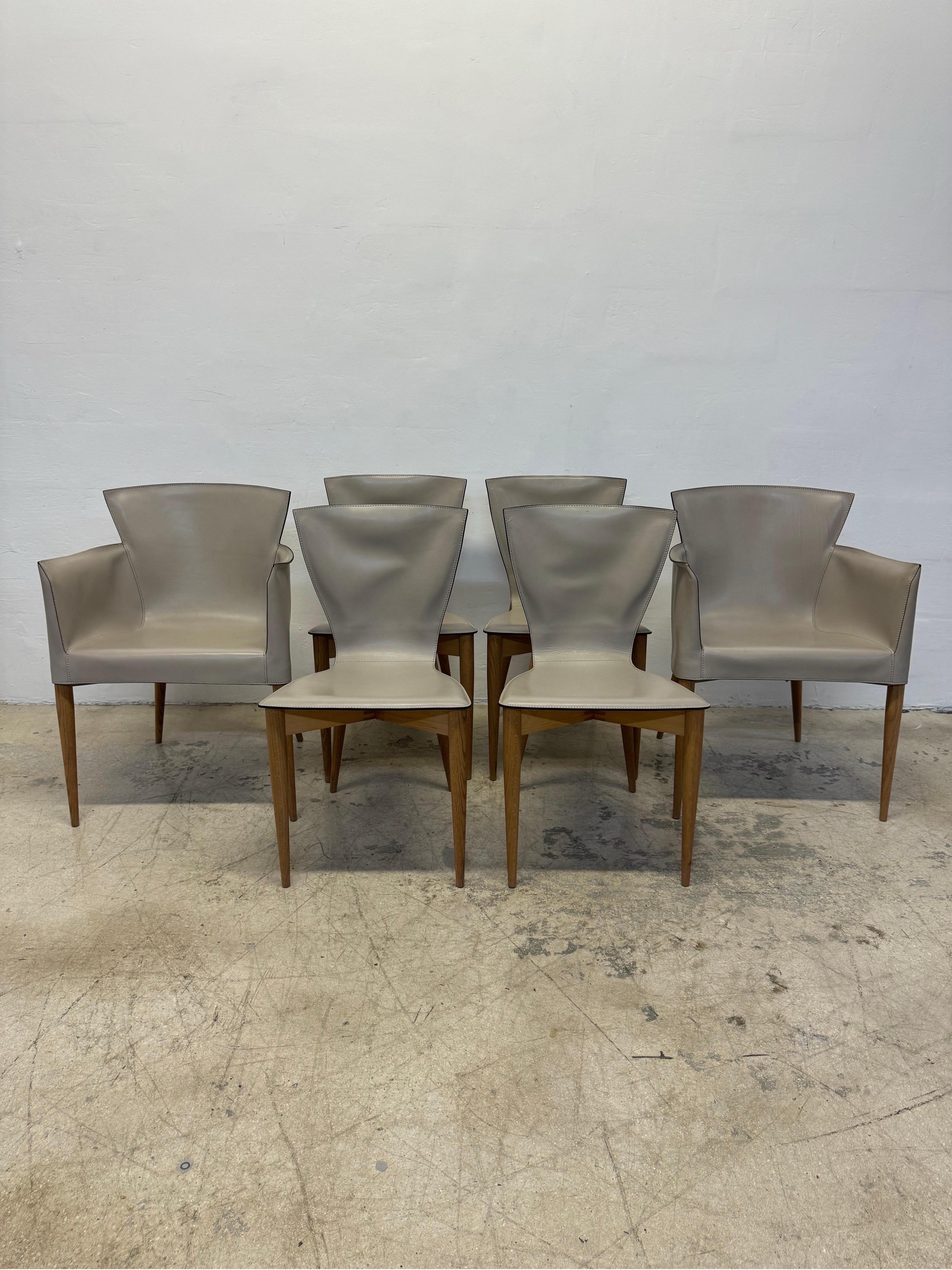 Set of six Vela dining chairs made with thick, high quality leather seats fitted over a wood frame. Deigned by Carlo Bartoli in the 1970s for Matteo Grassi.  This set is circa 1980s.

Dimensions
2 Arm Chairs - W22.5” D20.5” H31” SH18”
4 Chairs -
