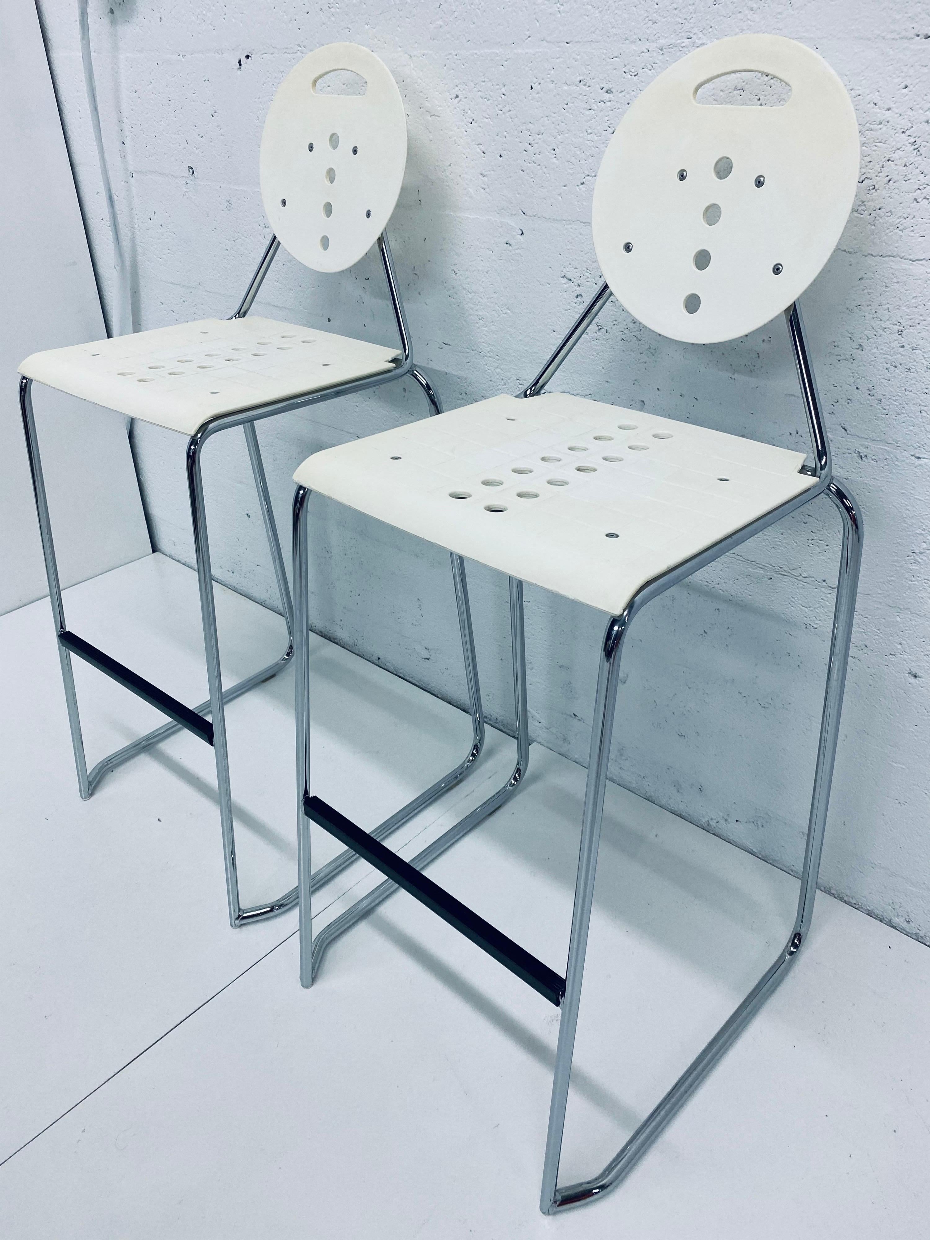 Pair of Postmodern Memphis style barstools by Carlo Bimbi and Nilo Gioacchini for Segis Italia, circa 1980s. Chairs are made of white moulded plastic attached to a tubular chrome frame. The chairs stack for easy storage. Some yellowing to plastic
