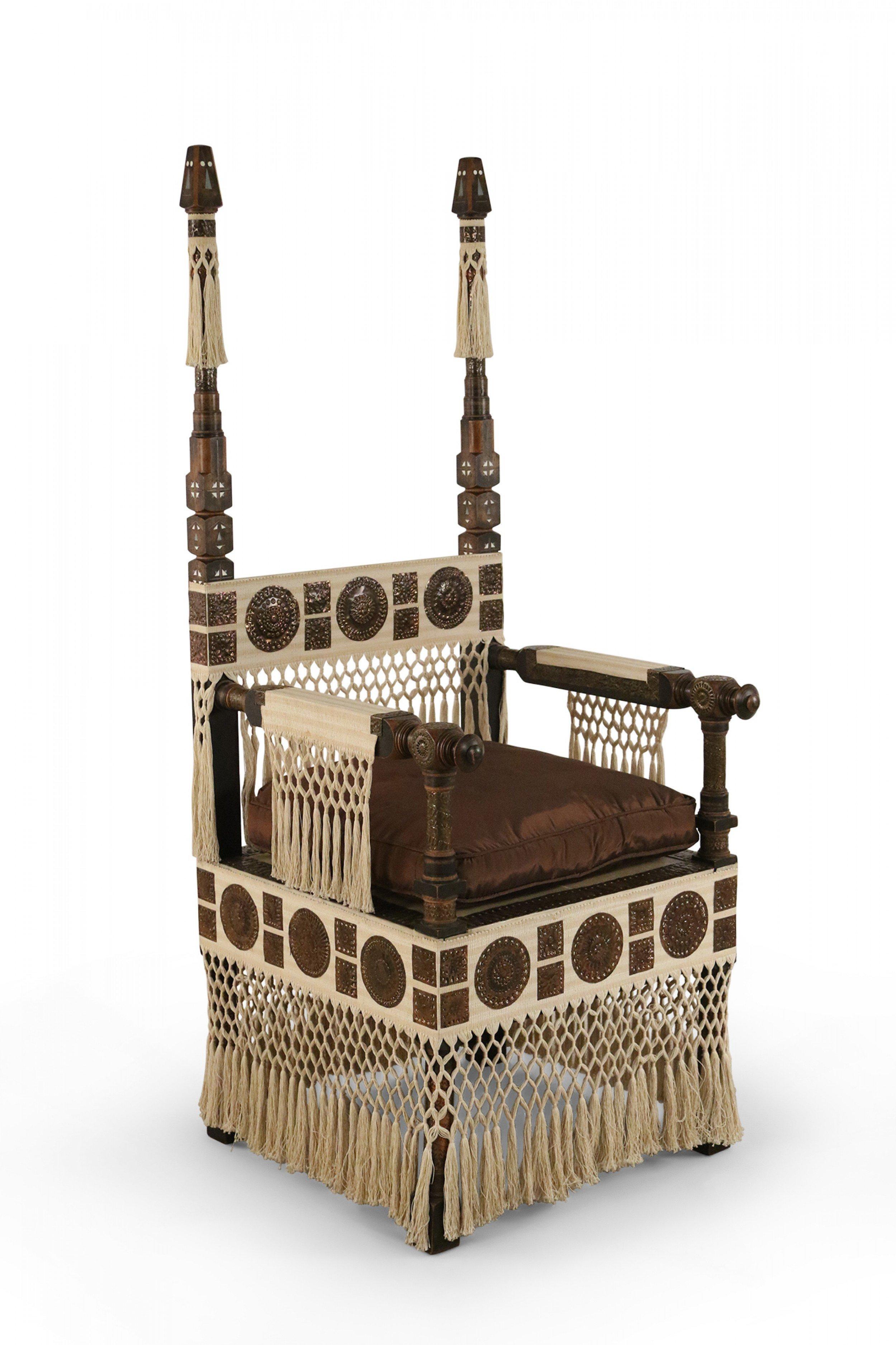 Italian Art Deco mahogany and walnut throne chair with decorative pewter and brass inlay, applied and embossed copper roundels, calfskin vellum seat with brown upholstered seat cushion, and beige fabric detail with woven tassels (Carlo Bugatti).