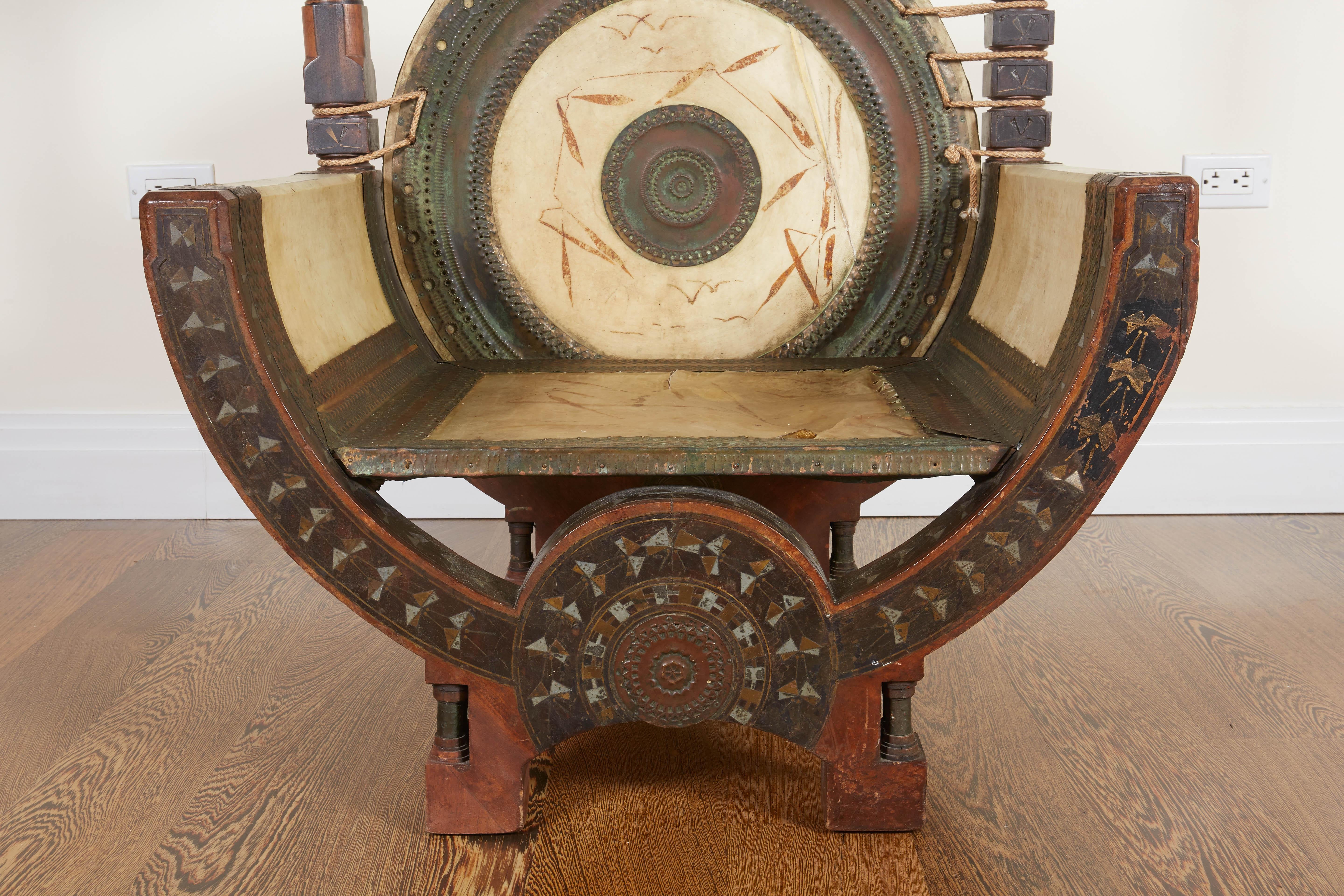 Of stylized curule form embellished in Bugatti's signature blend of Moorish and Japanese motives; with vellum hand-painted circular back and seat, and geometrical inlay and applied repoussé and pierced copper overall.