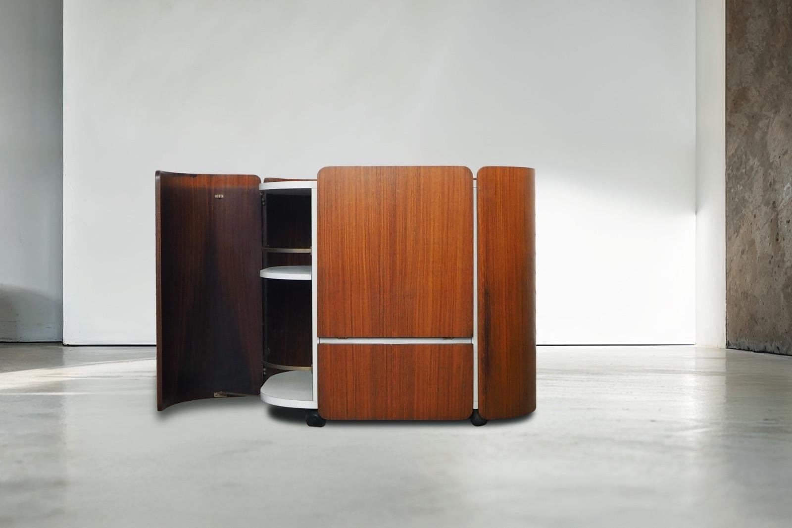 Raro mobile bar disegnato da Carlo de Carli per la manifattura Fiarm negli anni ’70. 
Questo pezzo è un perfetto esempio del design italiano organico e sperimentale del periodo: linee curve, funzionalità ingegnose e contrasti materici eleganti. Il