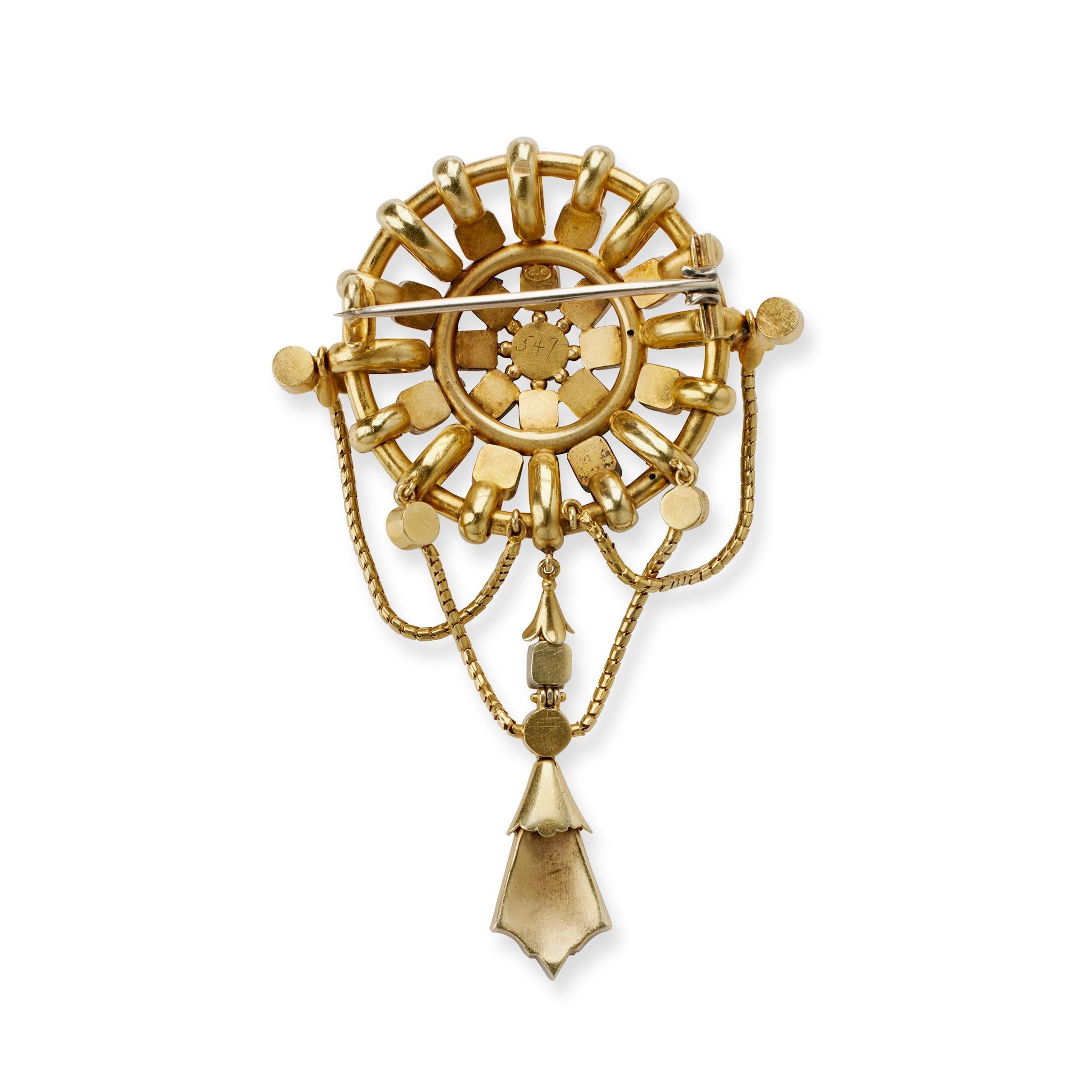 Dating from the 1880s, this emerald, seed peal and 18K gold brooch is signed by Carlo Giuliano, London. The brooch is designed as an 18K gold bombé boss of interlinked circles set with emerald-cut emeralds, highlighted by applied wirework and split