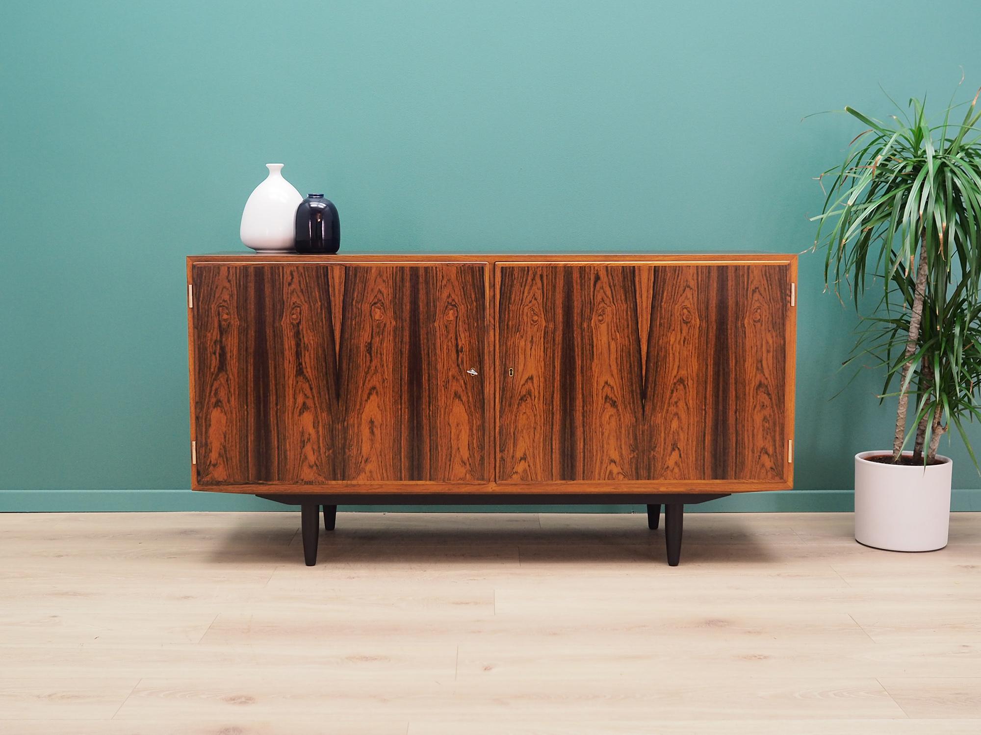 Brilliant cabinet from the 1960s-1970s. Minimalist form, Scandinavian design. The furniture is covered with rosewood veneer. Designed by Carlo Jensen, produced in the Hundevad & Co. manufactory. The cabinet has three stylish drawers and an
