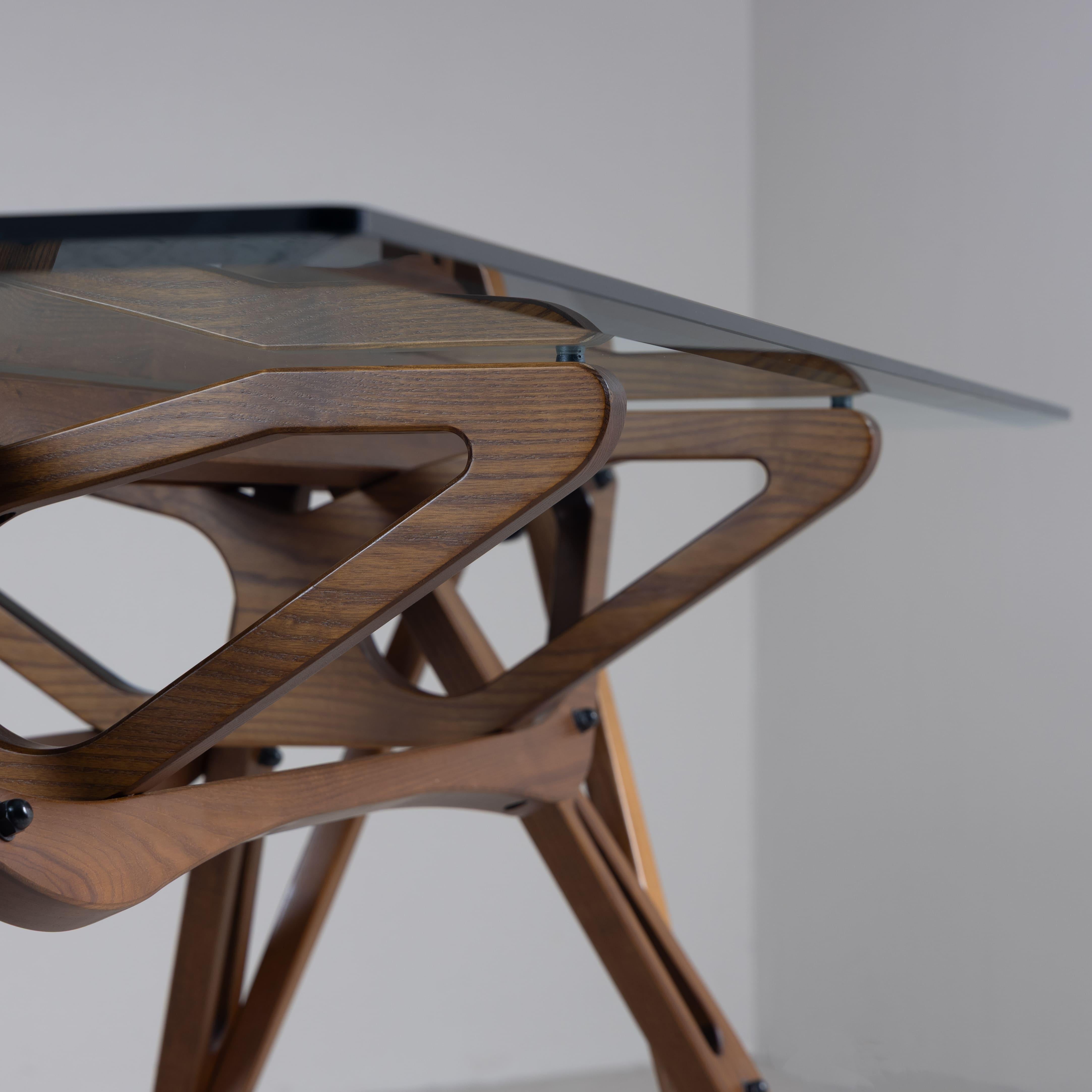 Table rectangulaire modèle Reale en bois et verre, conçue par Carlo Mollino en 1948 et produite par Zanotta. Les formes articulées et complexes de ce projet étonnent par l'intelligence constructive d'un mécanisme parfait, dans lequel chaque élément
