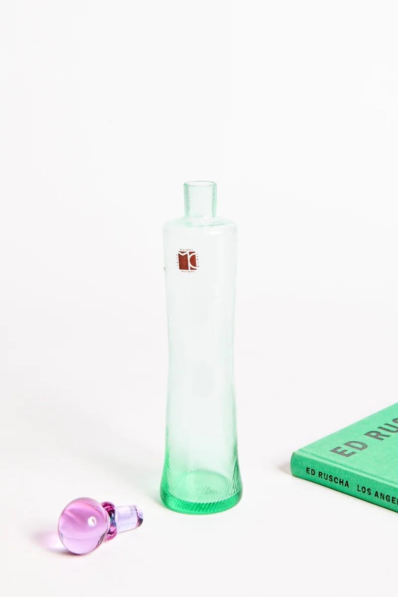 Elegant Carlo Moretti decanter in finely fluted sea green glass accented with a pale violet round stopper. 