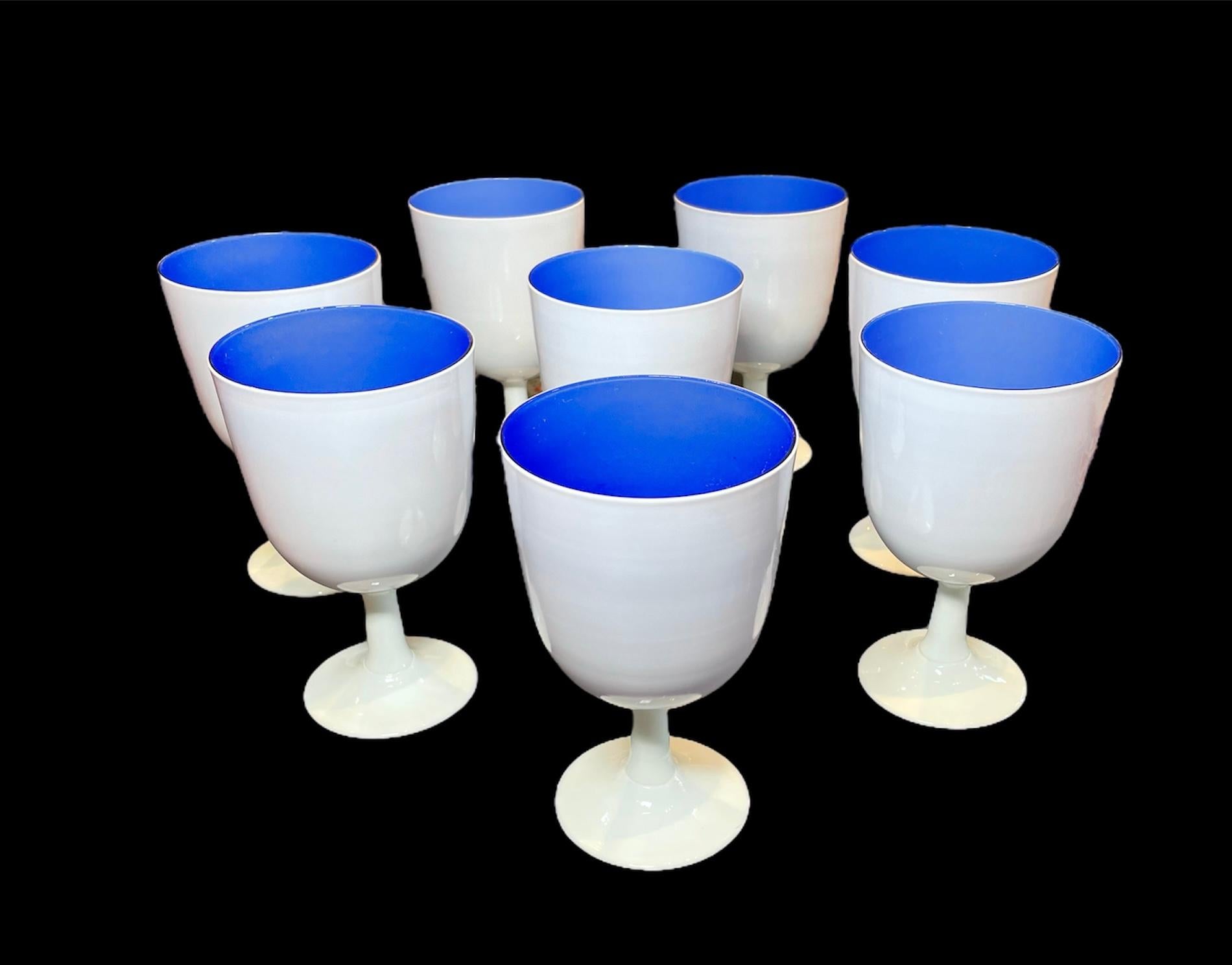 This is a Carlo Moretti set of 8 white and confined blue color. Murano glass goblets. It depicts a set of bell shaped goblets.