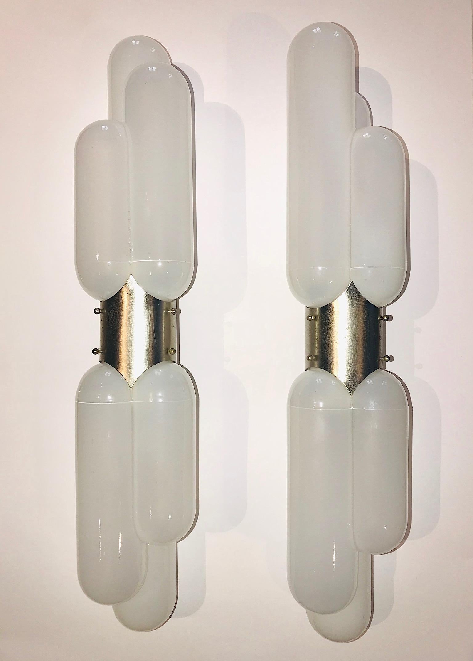 A wonderful pair of Italian Mid-Century Modern torpedo shape wall sconces by Carlo Nason for Mazzega, circa 1970. Milky white opaque mold blown shades are suspended on top and bottom of satin finish metal wall mounts. Each sconce has two lights and