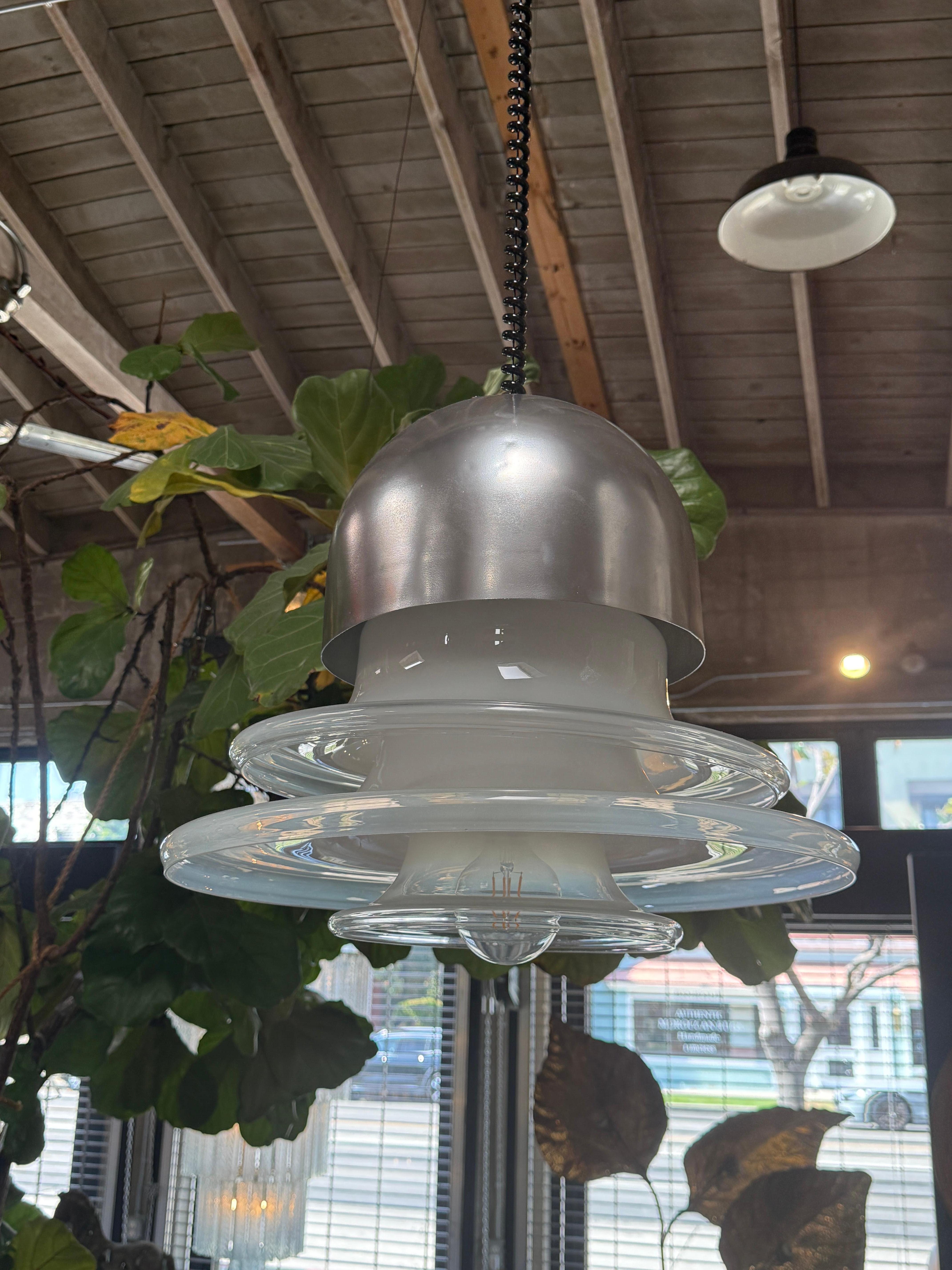 This distinctive pendant lamp combines mid-century modern and retro-futuristic elements with a touch of industrial charm. The lamp features:

Top Cap: A brushed aluminum dome that serves as the top housing, adding an industrial metallic