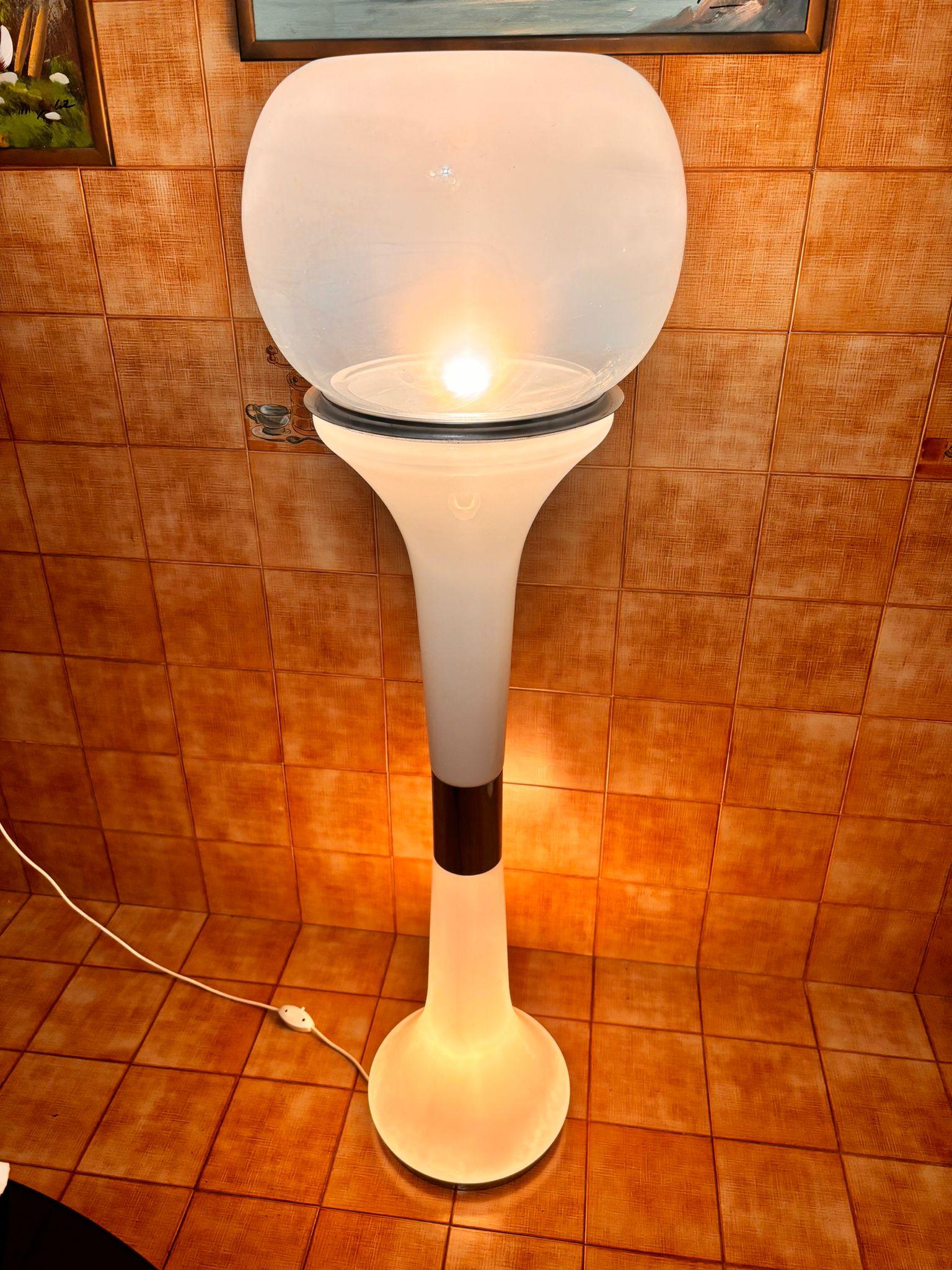 Diese Leuchte mit ihrer geschwungenen, modernen Form zeichnet sich durch ihr elegantes Design und das Spiel der Transparenzen aus. Der halbtransparente obere Diffusor filtert sanft das Licht und schafft eine warme und einladende Atmosphäre. Der