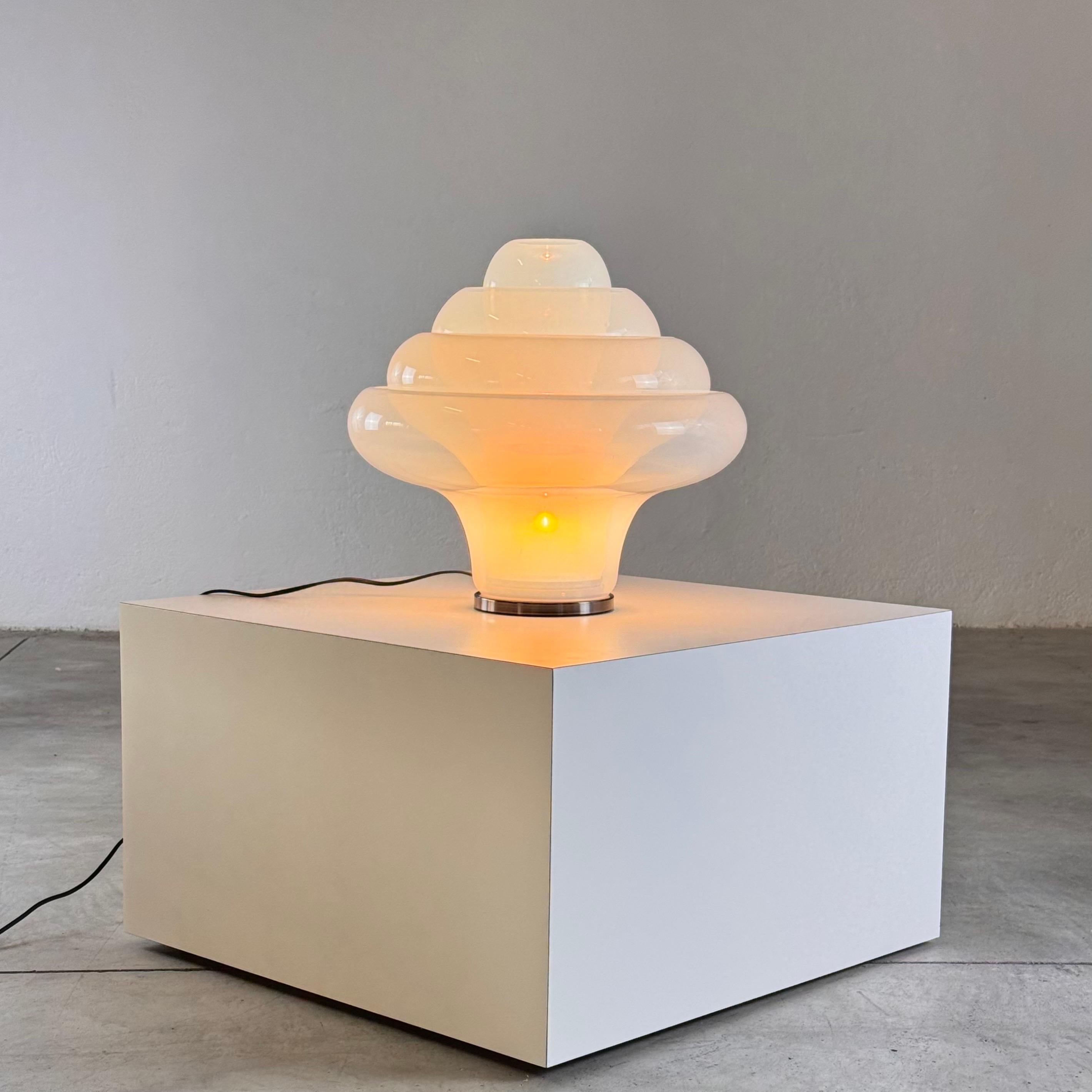 The LT305 'Lotus' table lamp, designed by Carlo Nason for Mazzega in the 1960s, is a stunning example of Italian craftsmanship and artistic vision. This particular piece, produced in the late 1990s, is made from exquisite opalescent glass and is in