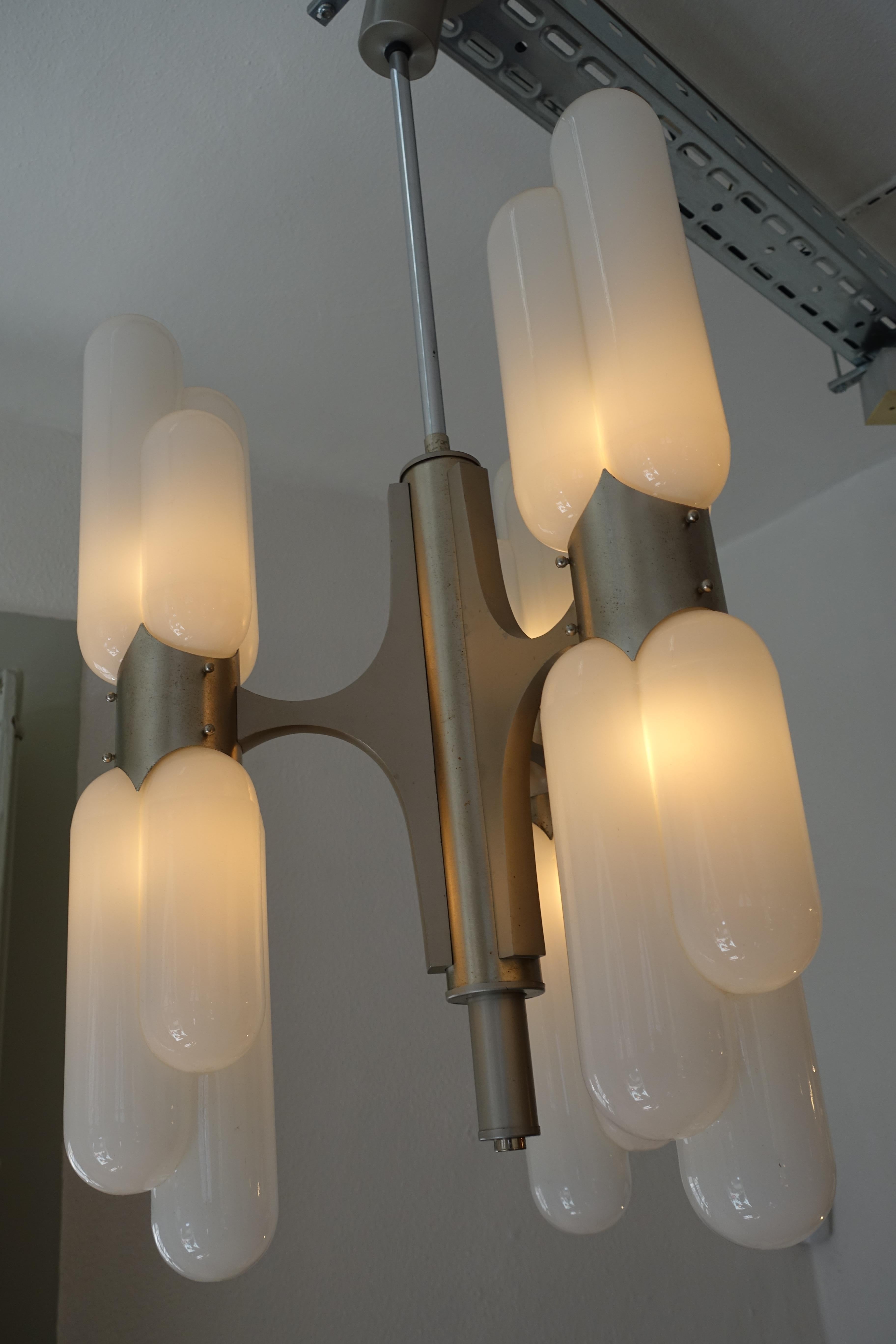 Mid-Century Modern Italian chandelier with three-arm carrying six double tube handblown glass tubes in opaline white glass. The brushed aluminum frame has a modernist / Space Age and stylish appearance.