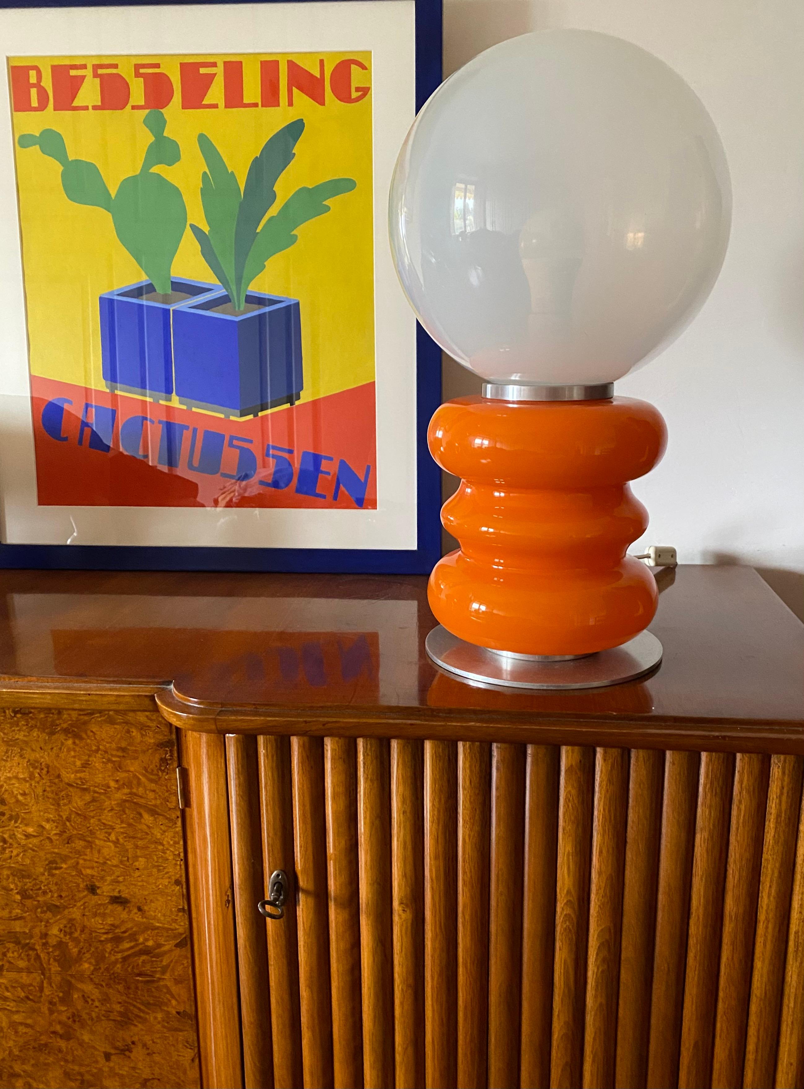 Lampe de table en verre de Murano de l'ère spatiale.

Conçu par Carlo Nason, AV Mazzega, Italie 1970

Verre demi-blanc opalin et verre orange. Aluminium chromé. Deux ampoules, l'une éclaire la sphère blanche, l'autre la base orange.

57 cm H - 32 cm