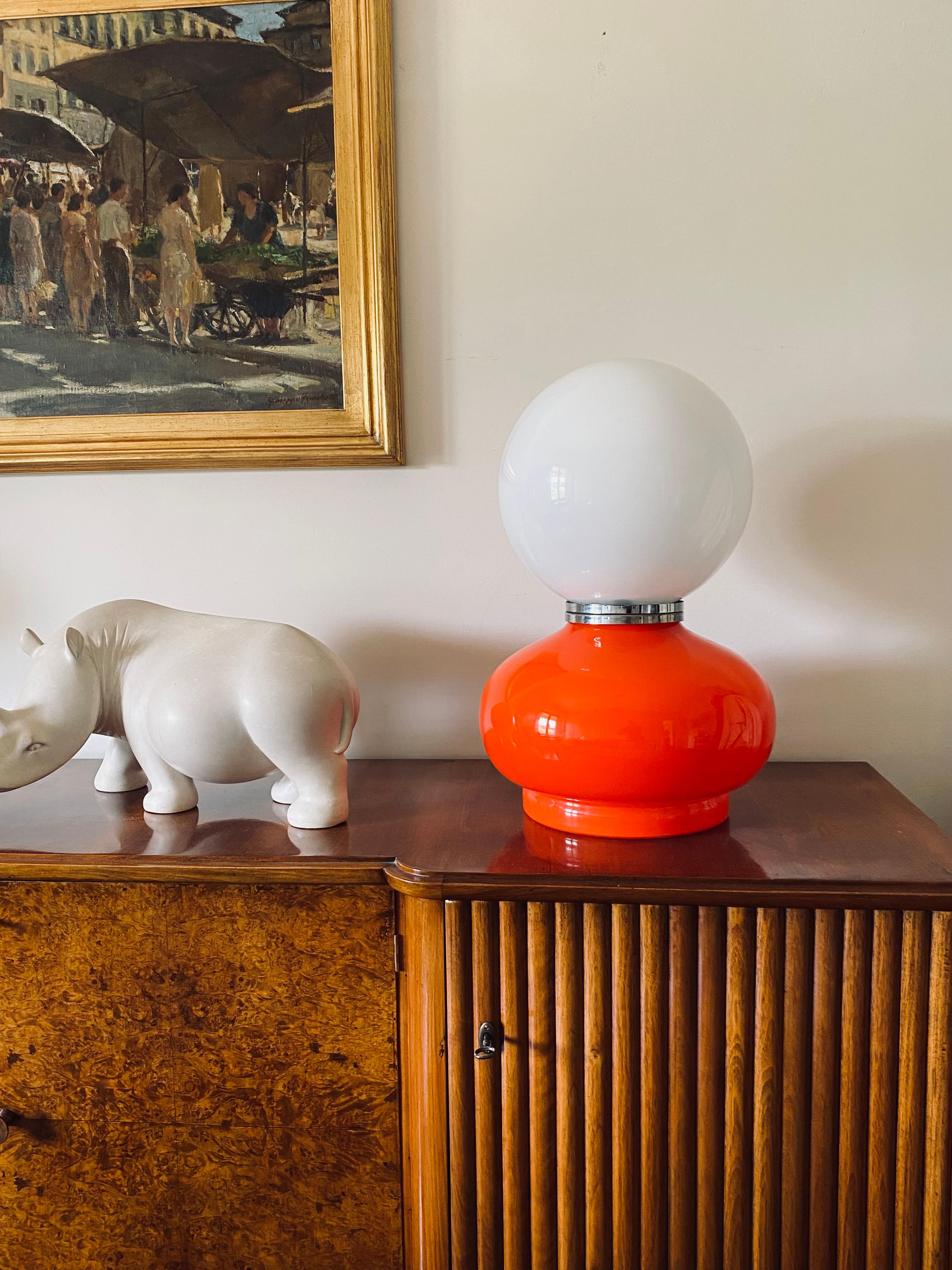 Tischlampe aus Murano-Glas, Space Age.

Entworfen von Carlo Nason, AV Mazzega, Italien 1970er Jahre

Opalin halb weißes Glas und rotes Glas. Verchromtes Aluminium. Zwei Glühbirnen, eine beleuchtet die weiße Kugel, die andere den orangenen