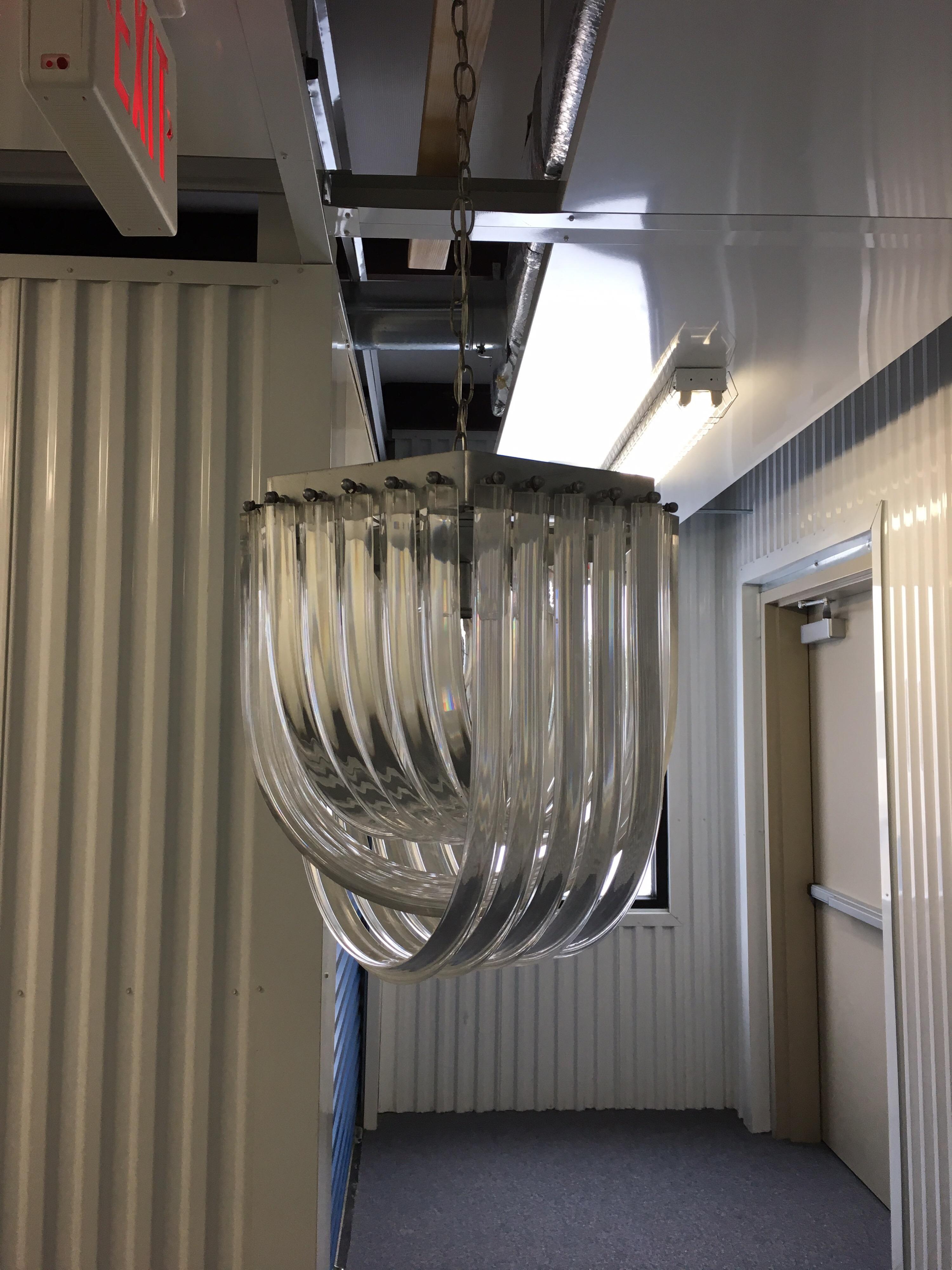 Carlo Nason style curved clear Lucite Triedri Prism chandelier, 1980. Glamorous acrylic crystal rod chandelier, circa 1970s-1980s. This sculptural round chandelier is designed of intertwining loops of clear twisted Lucite rods suspended from a