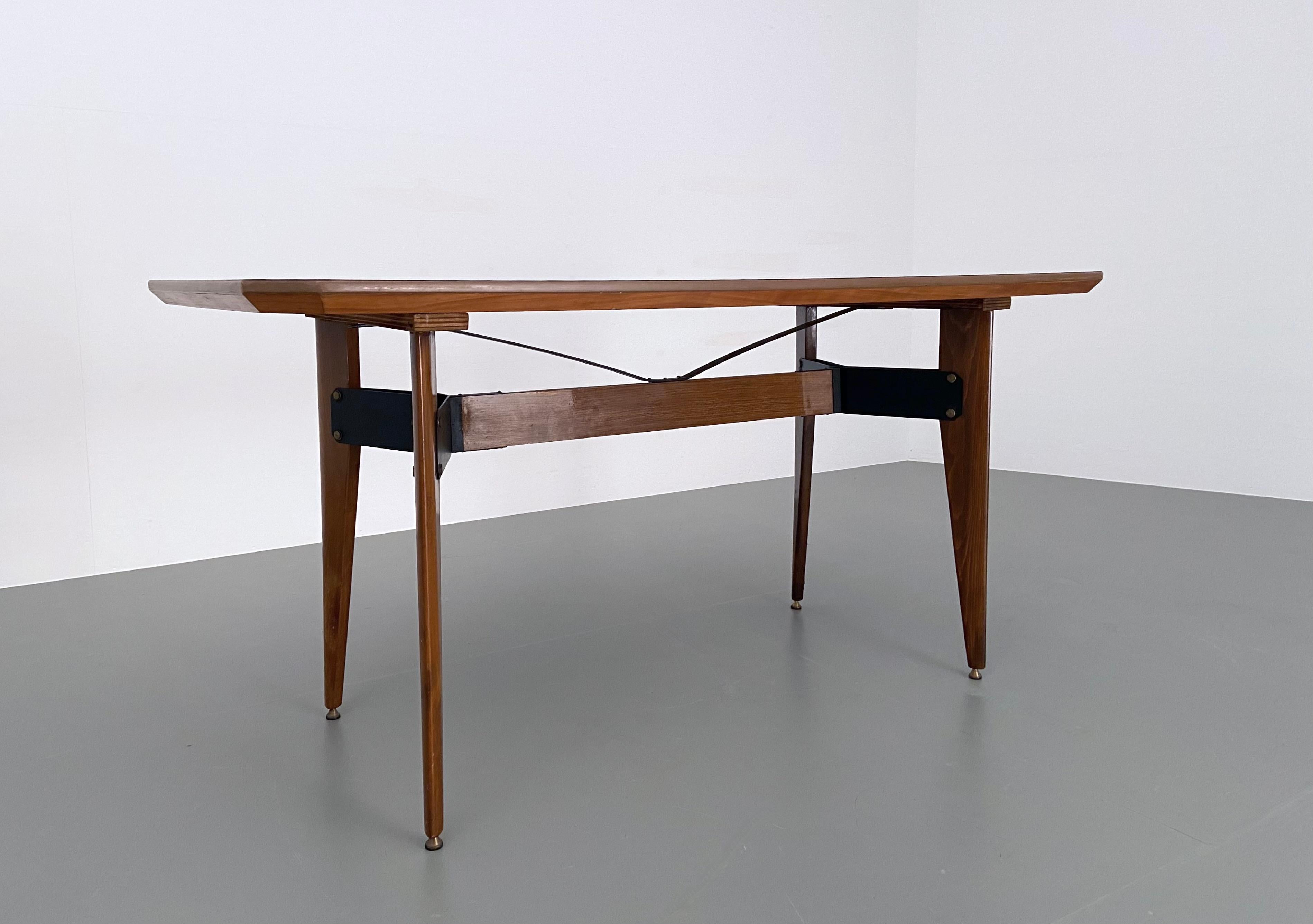 Smaller dining-room table with typical graceful Italian shapes. The table has somewhat flat and tapered legs and a V-shaped construction in metal and wood. Some nice details can be found back in the brass feet (!) and in the pleasant shape of the