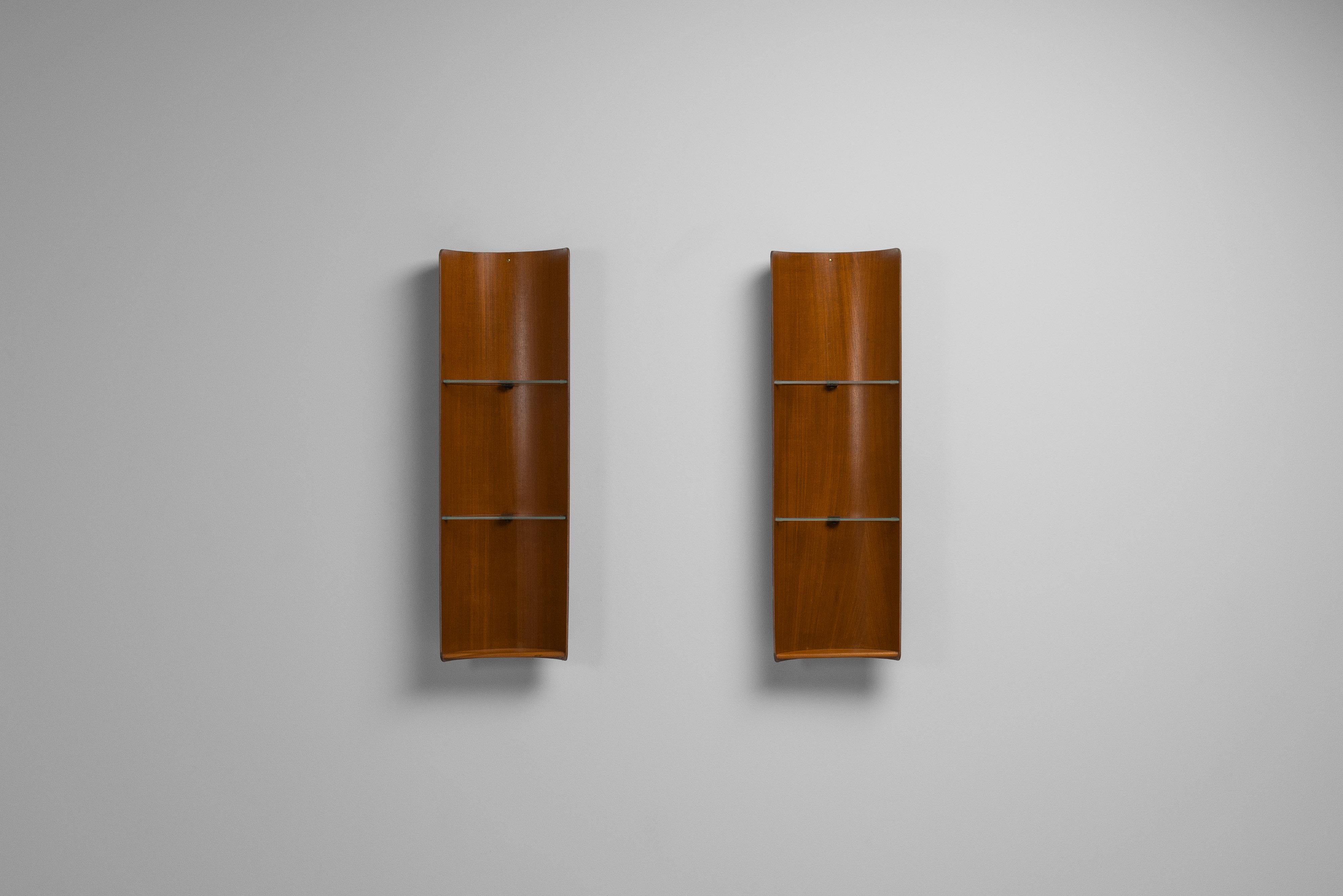 Beautiful pair of wall mounted display cabinets designed by Carlo Ratti and manufactured by Industria Legni Curvati in Italy in 1950. These cabinets are made of bent teak plywood and have a unique design. Each cabinet has two glass shelves that