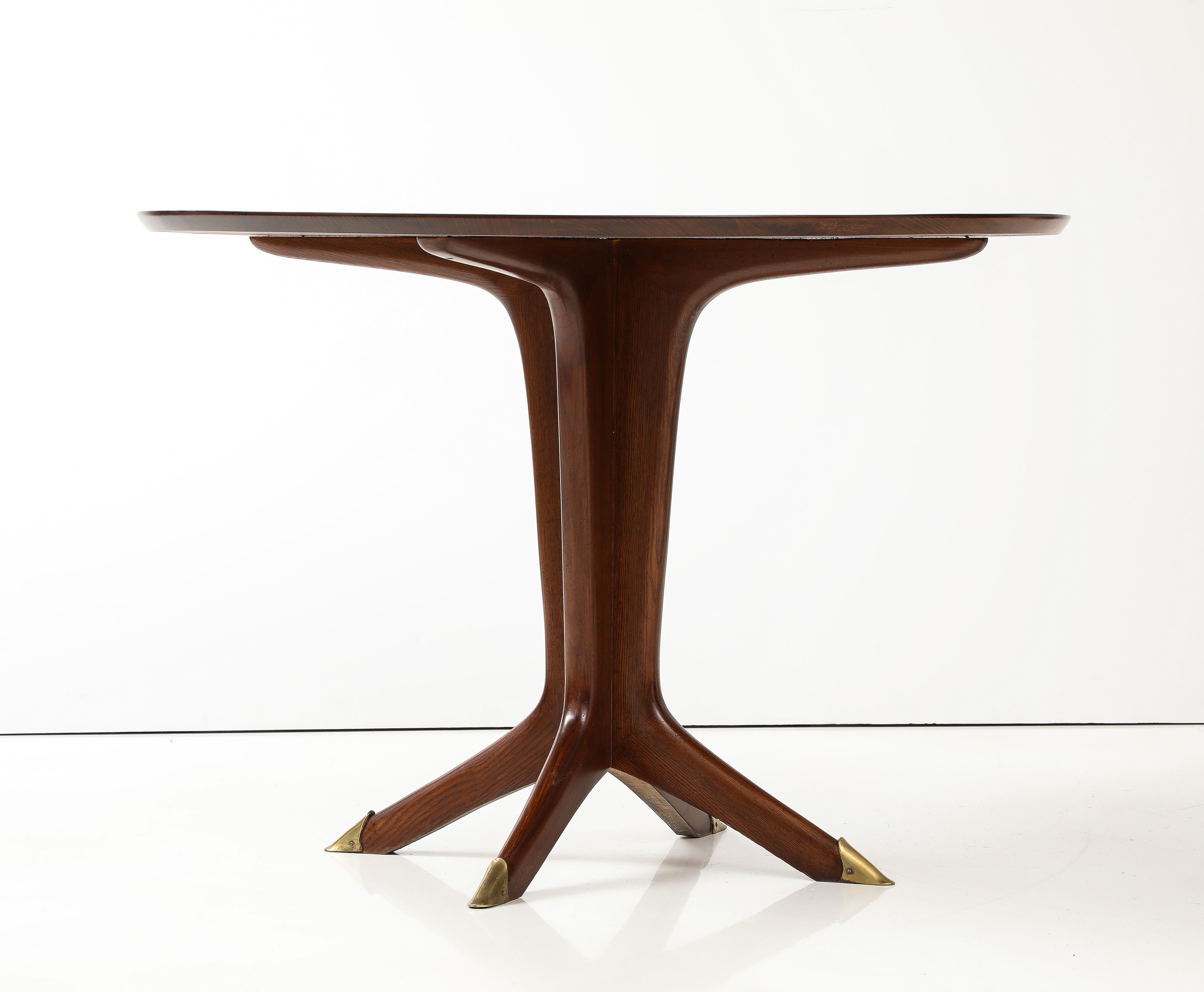 Un elegante tavolo da centro o da pranzo in legno di noce e ottone progettato  di Carlo Ratti, all'incirca all'inizio degli anni Cinquanta. Il piano circolare è sostenuto da una base a piedistallo che termina con un design a quattro piedi che poggia