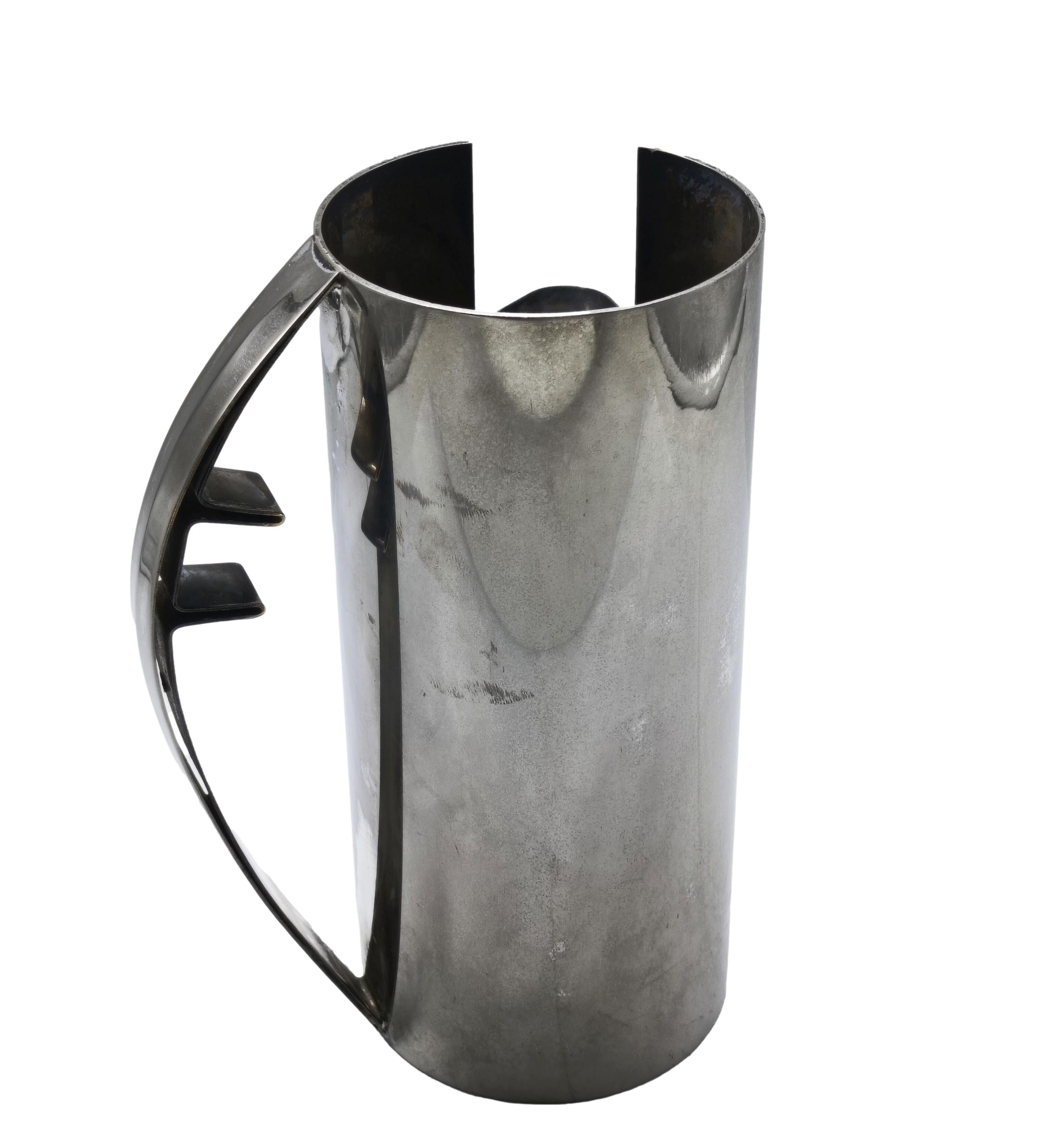 Una rara brocca scultorea disegnata dall'architetto Carlo Scarpa per Cleto Munari nel 1977. Presenta una forma cilindrica pulita, un beccuccio angolare e una maniglia ricurva che esprimono il minimalismo architettonico tipico di Scarpa. Firmato e