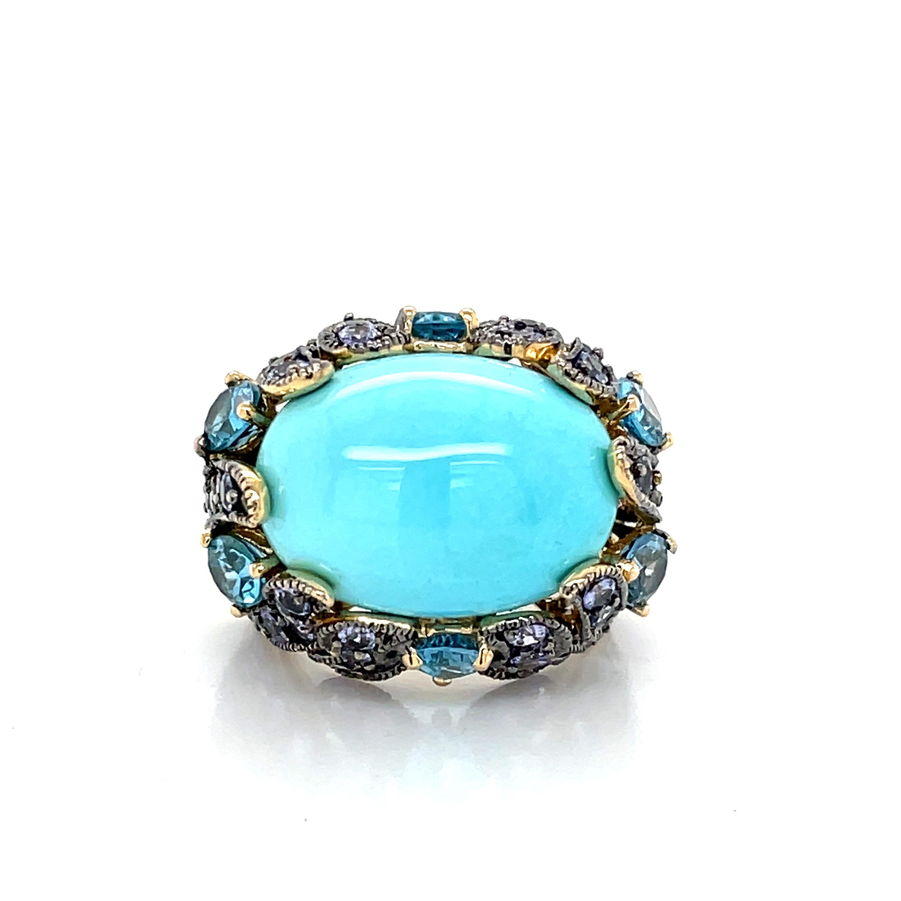 A  stunning 17mm x 13mm robin's egg blue oval turquoise cabochon is engaged in an opulent oxidized gold setting with six .25 carat pear shaped facet cut vibrant blue topaz stones and multiple brilliant round faceted violet color tanzanite giving
