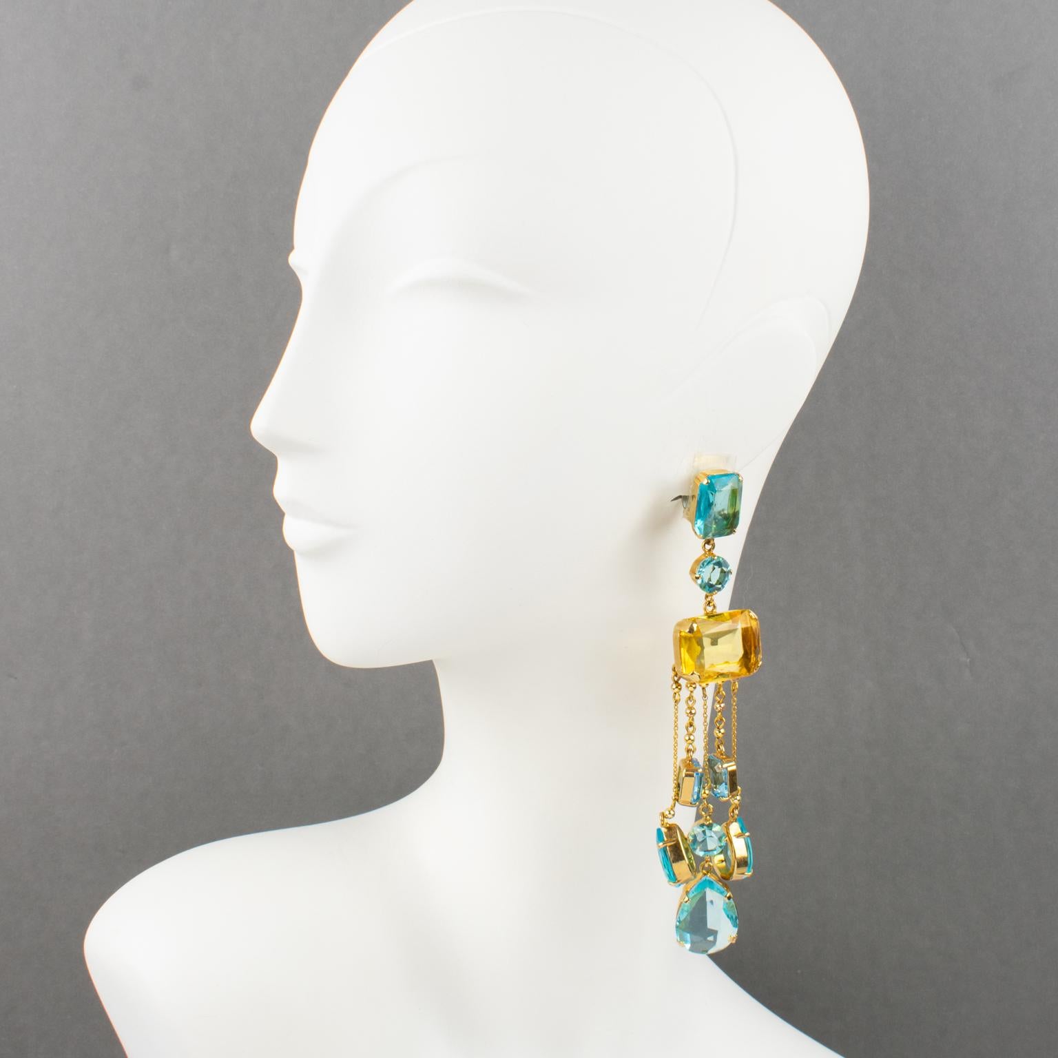 Carlo Zini designed those sophisticated dangling clip-on earrings. They feature an extra-long shoulder-duster geometric shape with gilded metal framing ornate with dangling charms. The aquamarine, turquoise, and yellow topaz colored-crystal