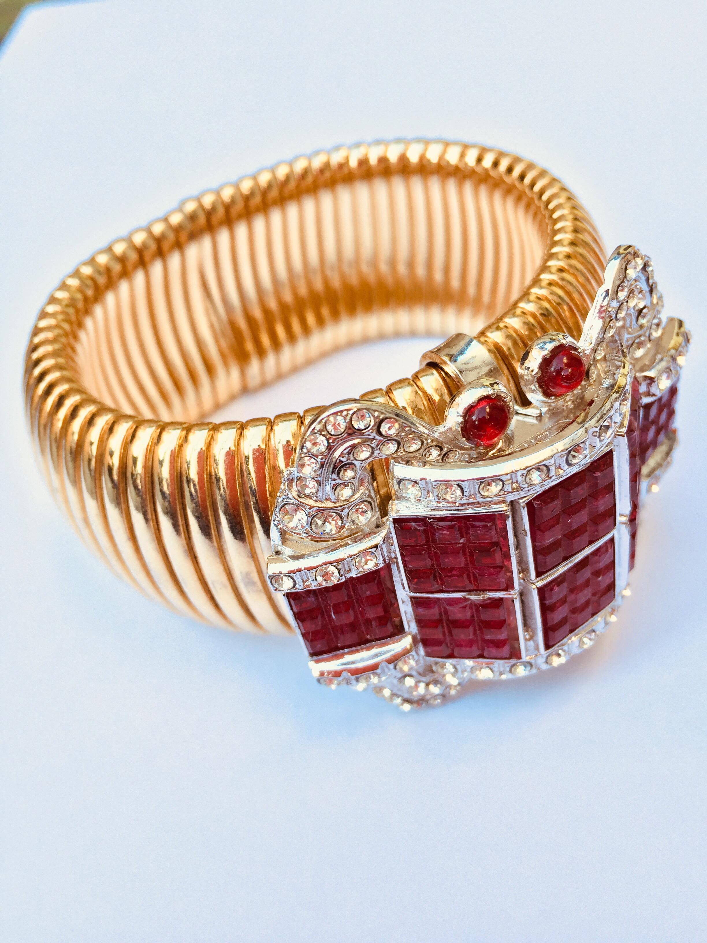 An Italian vintage tubogas bracelet by the Milanese bijoux designer Carlo Zini Milano, an Italian hand-creation inspired to 1940s style, in golden metal decorated with a ruby like stones and crystals buckle signed ZINI. 
Inner circumference is 18