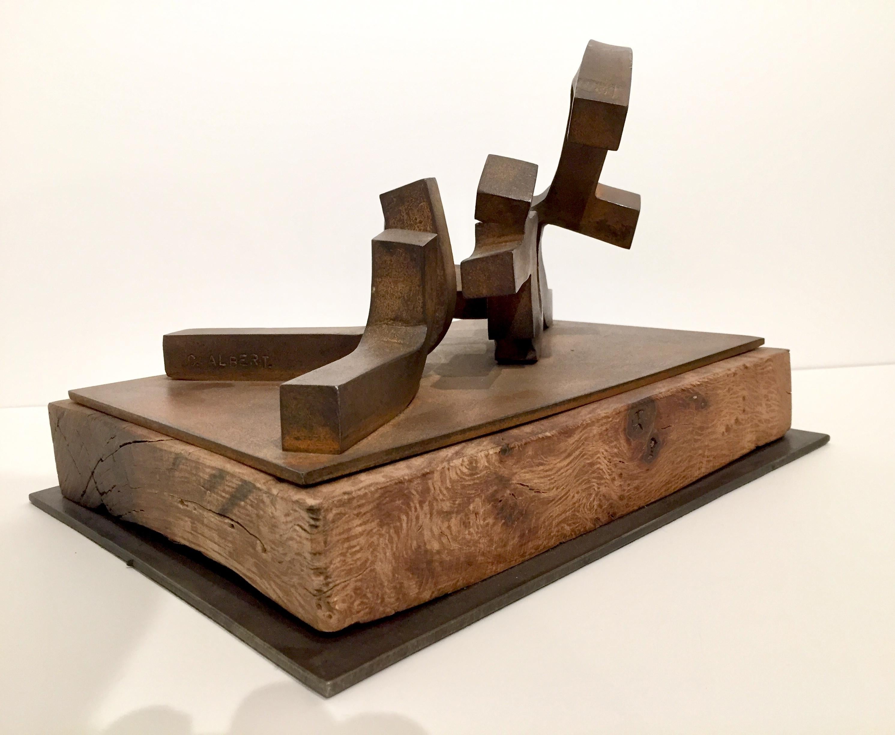 This is a 3 dimensional sculpture by Spanish abstract expressionist, Carlos Albert in reddish gray forged steel on a light natural wood base.  

Carlos Albert is a graduate of the School of Fine Arts at the Universidad de Complutense in Madrid,