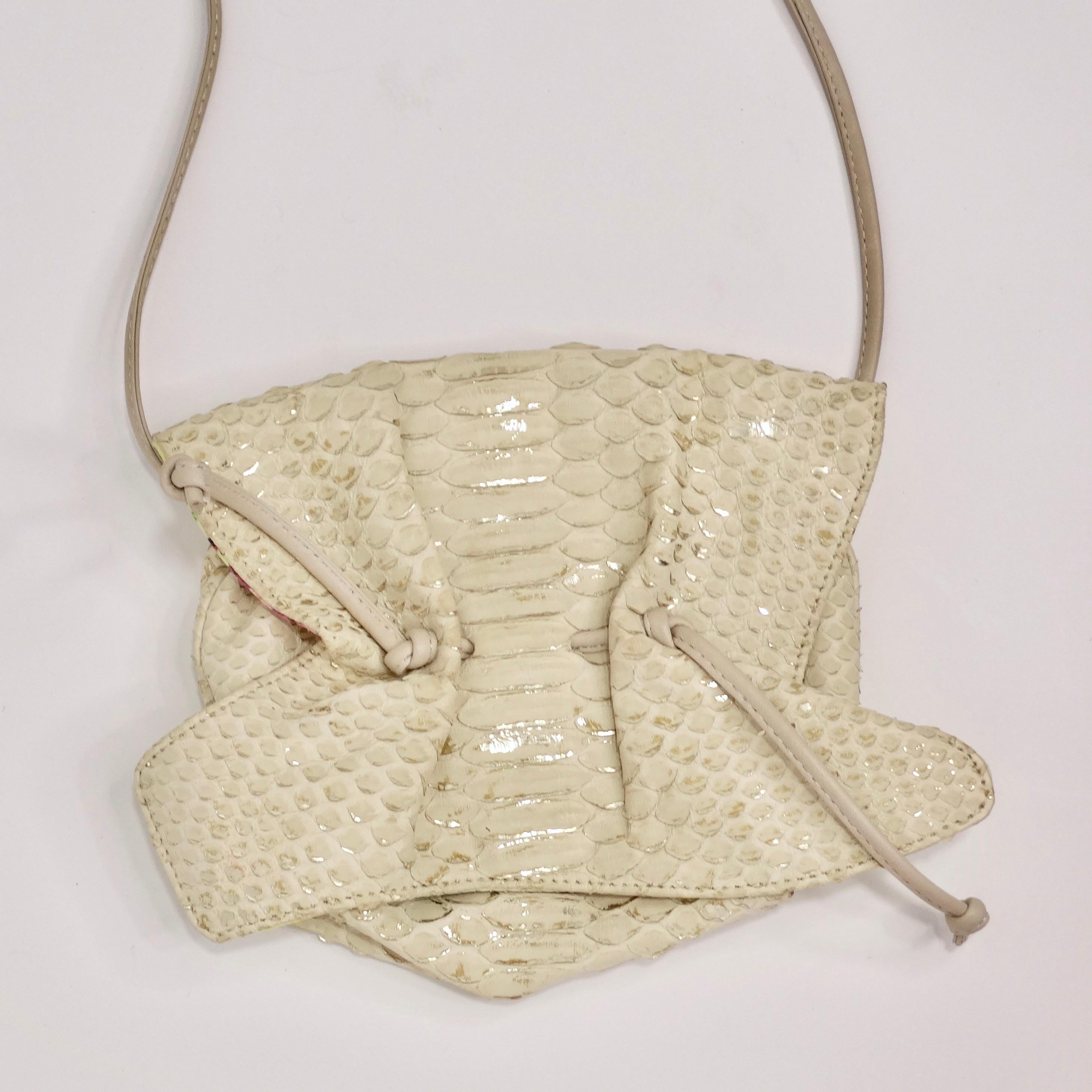 Discover the perfect blend of modern elegance and vintage charm with the Carlos Falchi Crossbody Mini Drawstring Bag. This handbag boasts a neutral creme-colored faux snake skin fabric with metallic silver accents, adding a touch of sophistication