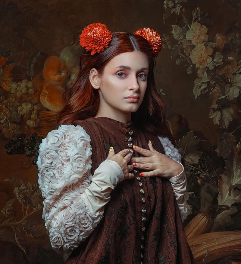 An Unexpected Visitor displays a female figure posed in Victorian-inspired clothing while incorporating a touch of modern influence with bright orange Chrysanthemum's laying on the model's toned hair. The piece contains beautiful earth tones such as