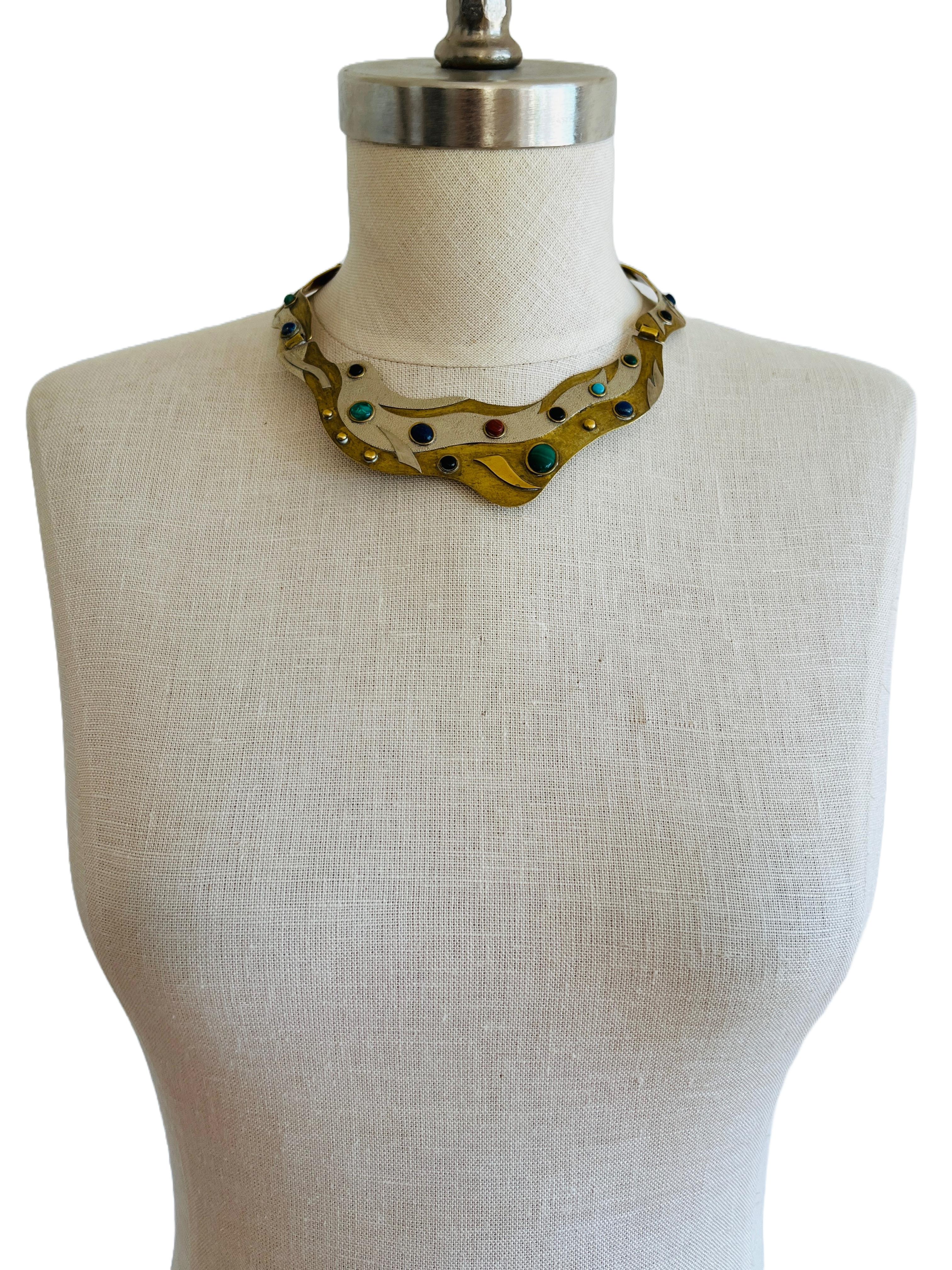 This stylish vintage necklace is a masterpiece of artistic jewelry from the mid-20th century. The piece features a unique and flowing design, with a central part that  resembles a bird in flight. Crafted from brass with silver overlay accents, the