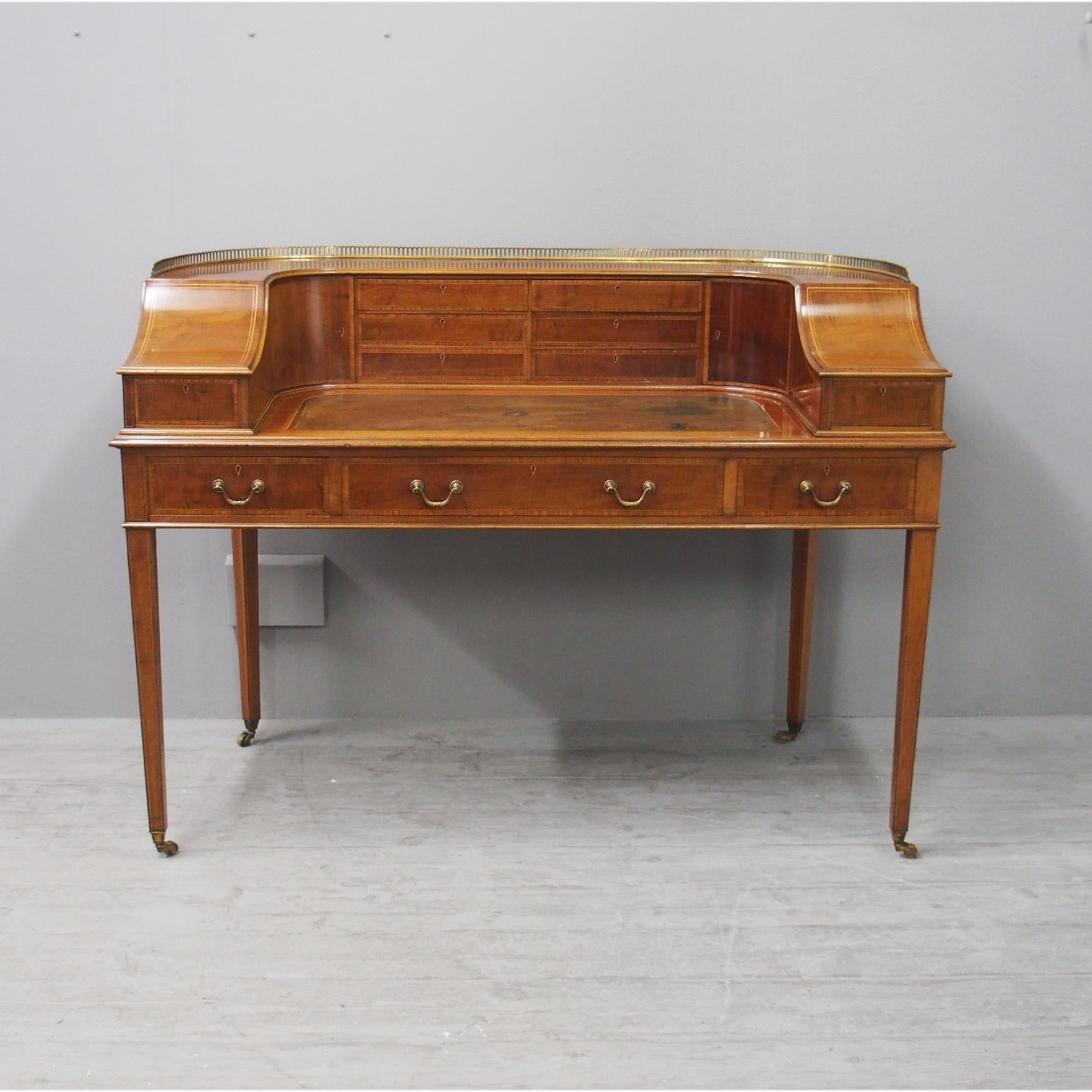 Mahogany and satinwood crossbanded Carlton House desk by Gillows of Lancaster, circa 1860. With open brass gallery to the top above a configuration of 8 drawers and 3 cupboards with satinwood inlay. There are a further set of 3 drawers below this,