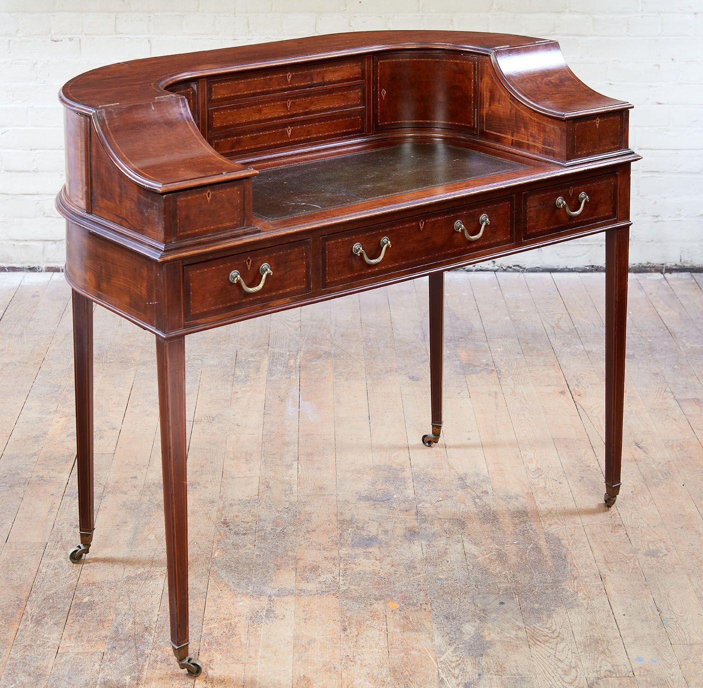 A Carlton House writing desk in wonderful fiddlegrain mahogany with a D shaped platform surrounded a series of raised drawers and covered compartments featuring fine satinwood inlays arranged in a curve around a leather writing surface, above three