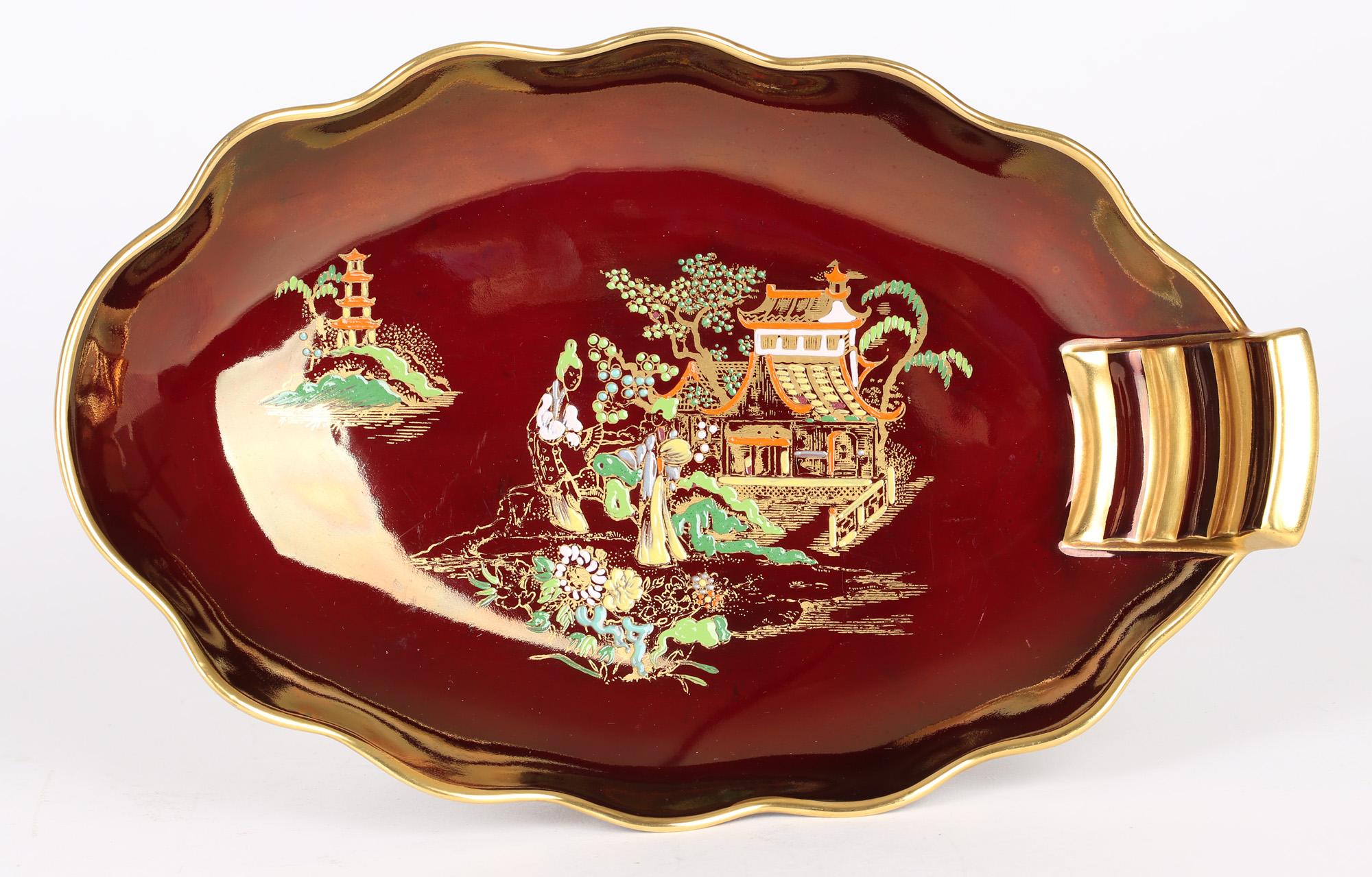 A finely made Art Deco Carlton Ware pottery Rouge Royal Pagoda pattern oval sweet meat dish dating between 1935 and 1955. The dish stands on a narrow oval shaped foot with a wider shallow shaped body with a fluted rim and with a raised molded