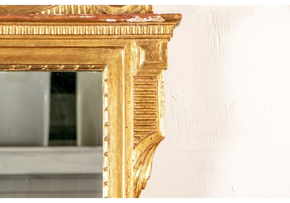 The floral urn with angular handles flanked by beaded strands and large acanthus leaves. All resting on a scrolled pediment. The surround with upper and lower carved fluted details with leaves. Inner long beaded surround. Pine cone form terminals.