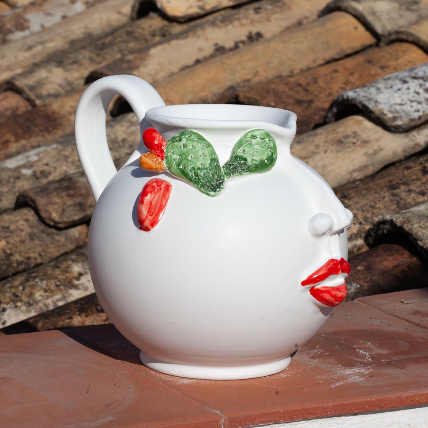 Handcrafted of matte-white-glazed ceramic by Patrizia Italiano as a tribute to the inebriating folklore of Sicilian local markets, this anthropomorphic pitcher boasts a generous silhouette embellished with colorful enamels accenting its traits. Its