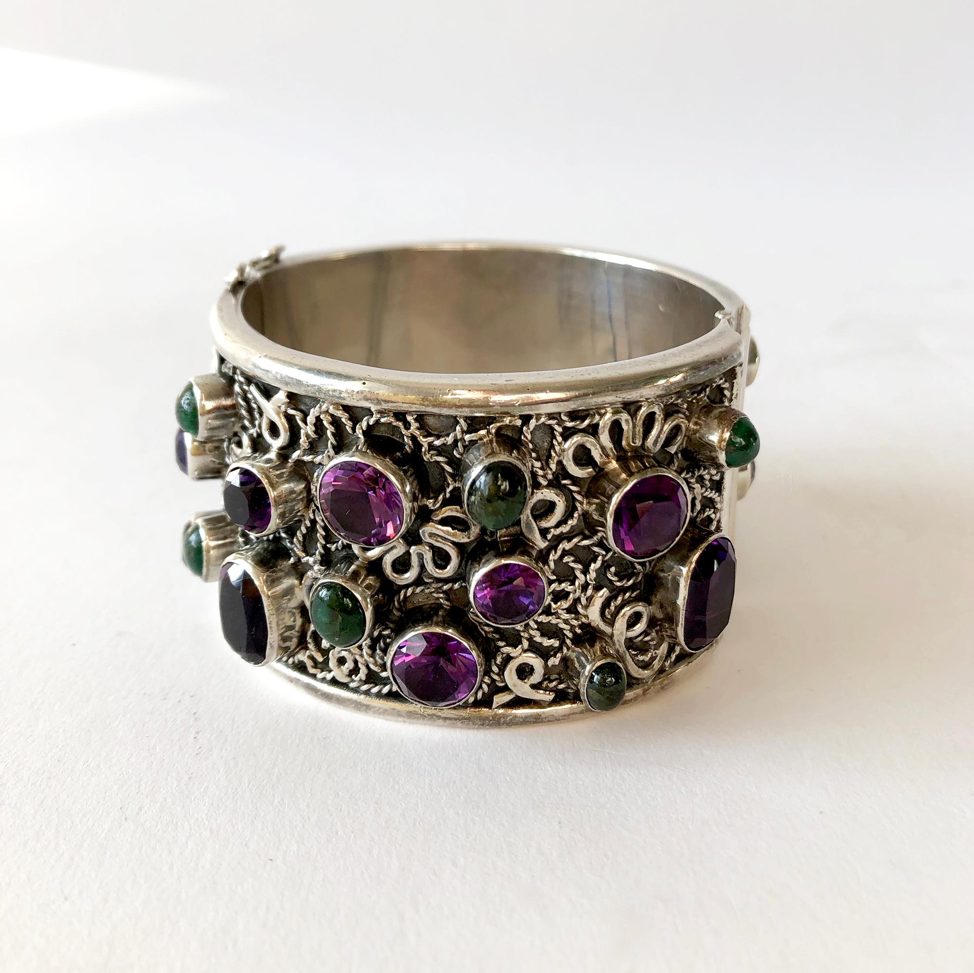 Wide, hinged bangle cuff bracelet encrusted with faceted amethyst and green gemstones created by Carmen Beckman of Mexico.  Bracelet measures 1.625
