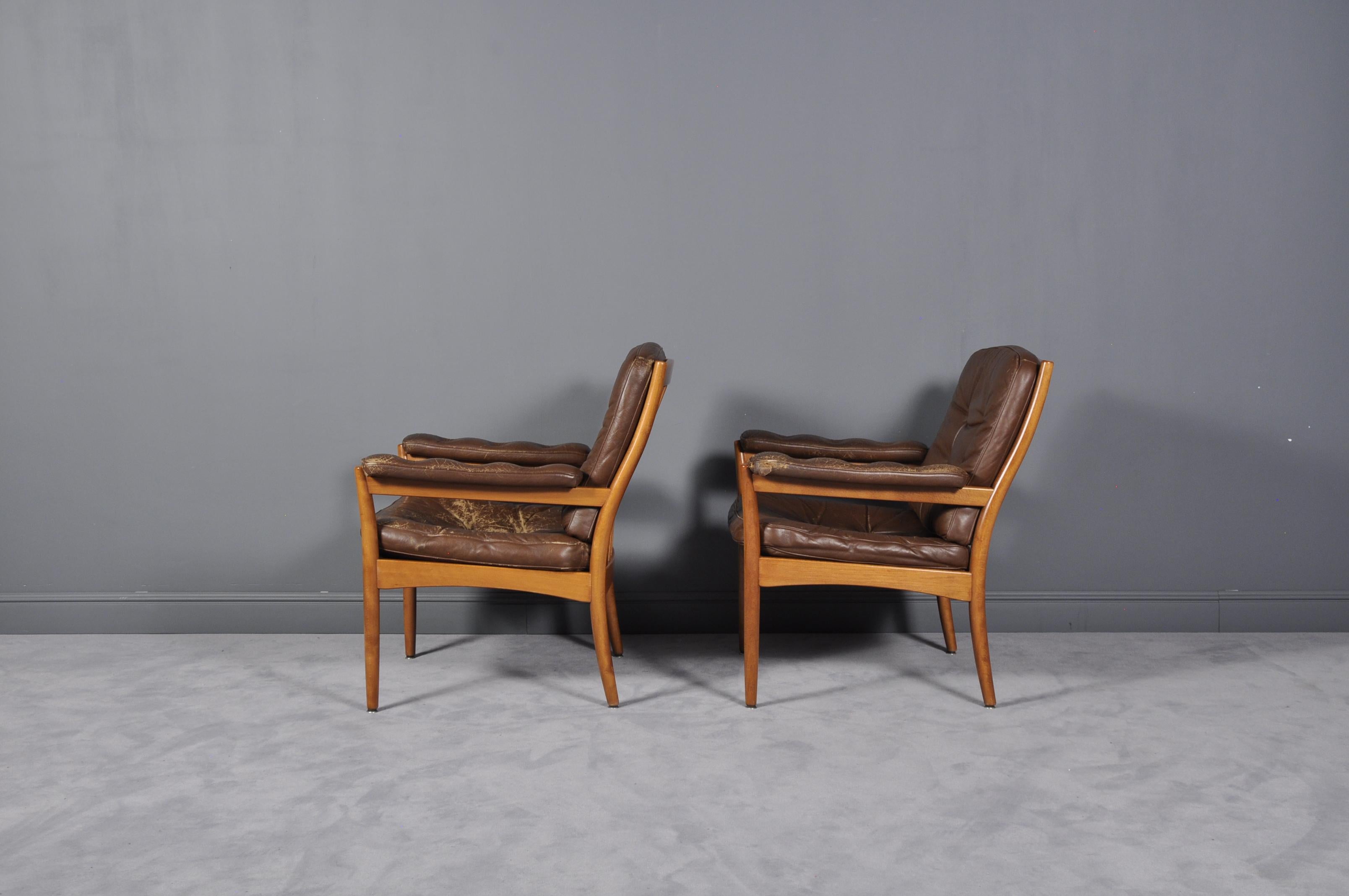 This pair of model Carmen easy chairs was produced by Göte Möbler, a Swedish manufacturer, and dates to the 1970s. The comfortable pieces feature hardwood frames and soft brown leather with buttoned cushions. They are labeled with the makers mark