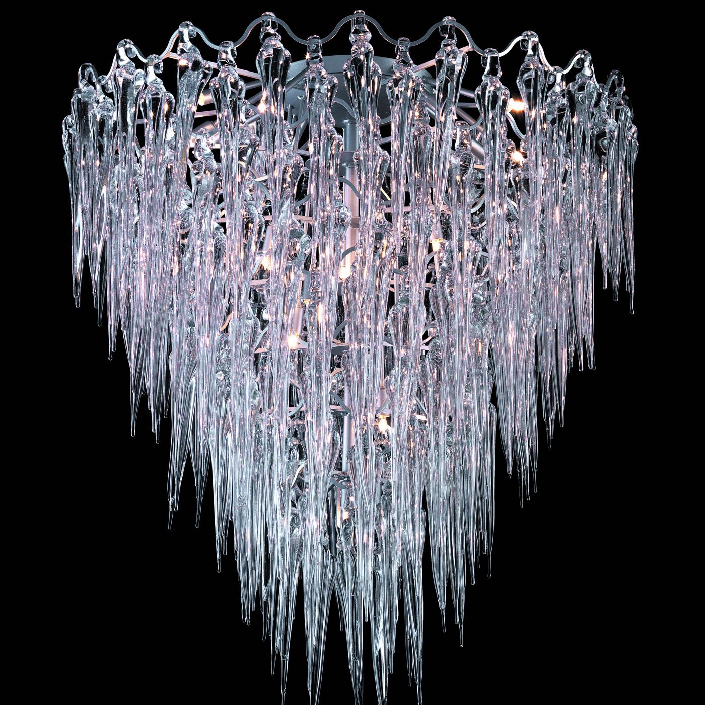 A sinuous metal frame sustains the hypnotic ensemble made of countless stalactites in clear glass that creates the splendid shape of this chandelier tapering downwards. A majestic object of decor also when off, this exquisite chandelier is at its