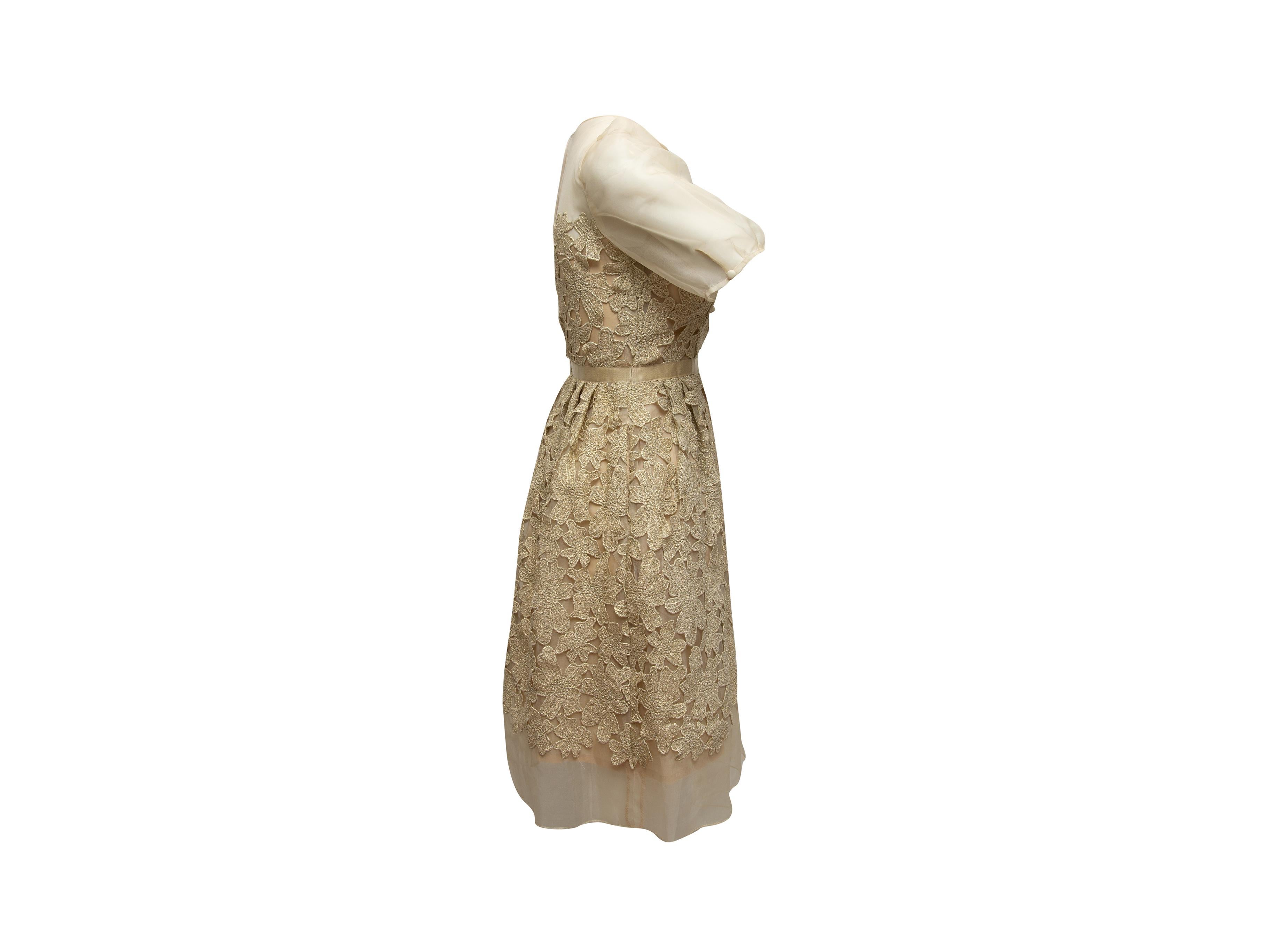 Product details: Beige and metallic gold floral patterned dress by Carmen Marc Valvo. Crew neck. Sheer short sleeves. Zip and button closures at back. 30