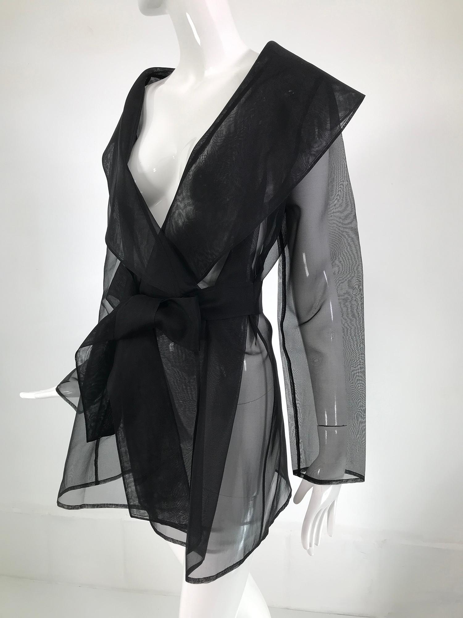 Carmen Marc Valvo sheer black wool organza evening jacket from the 1990s. The perfect evening cover up with a deep open neckline and a wide shawl collar, there is an attached waist self belt. The jacket falls to the mid to lower thigh, depending on