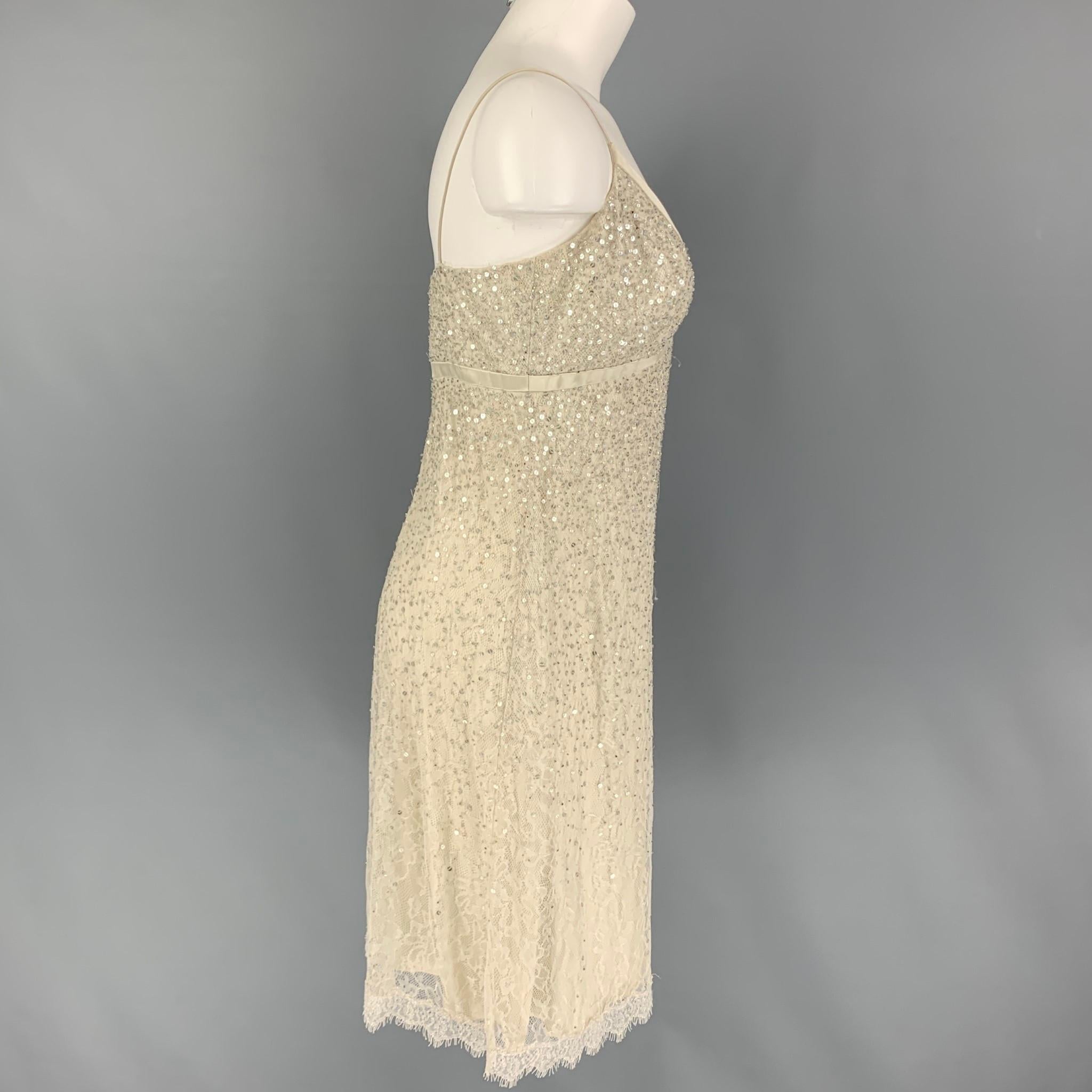 CARMEN MARC VALVO Collection cocktail dress comes in a off white lace material featuring sequin details, satin trim, spaghetti straps, and a back zip up closure. 

Very Good Pre-Owned Condition.
Marked: 6

Measurements:

Bust: 32 in.
Hip: 27