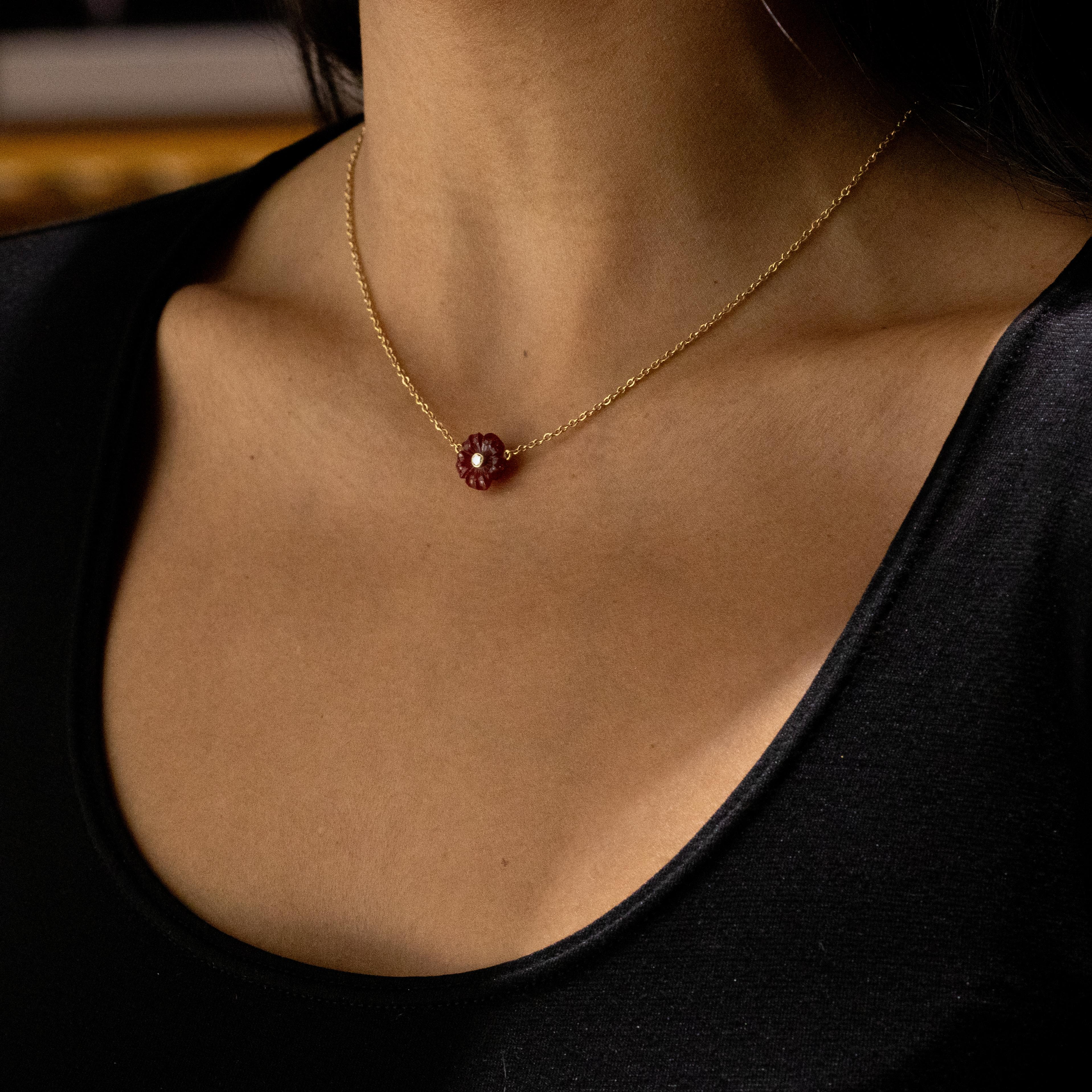 This gorgeous carnelian flower necklace is beautifully complemented by a wonderfully bright round brilliant cut diamond at its centre. The diamond is secured in a rub-over setting and weighs an estimated 0.03 carats.

The pendant is attached to a