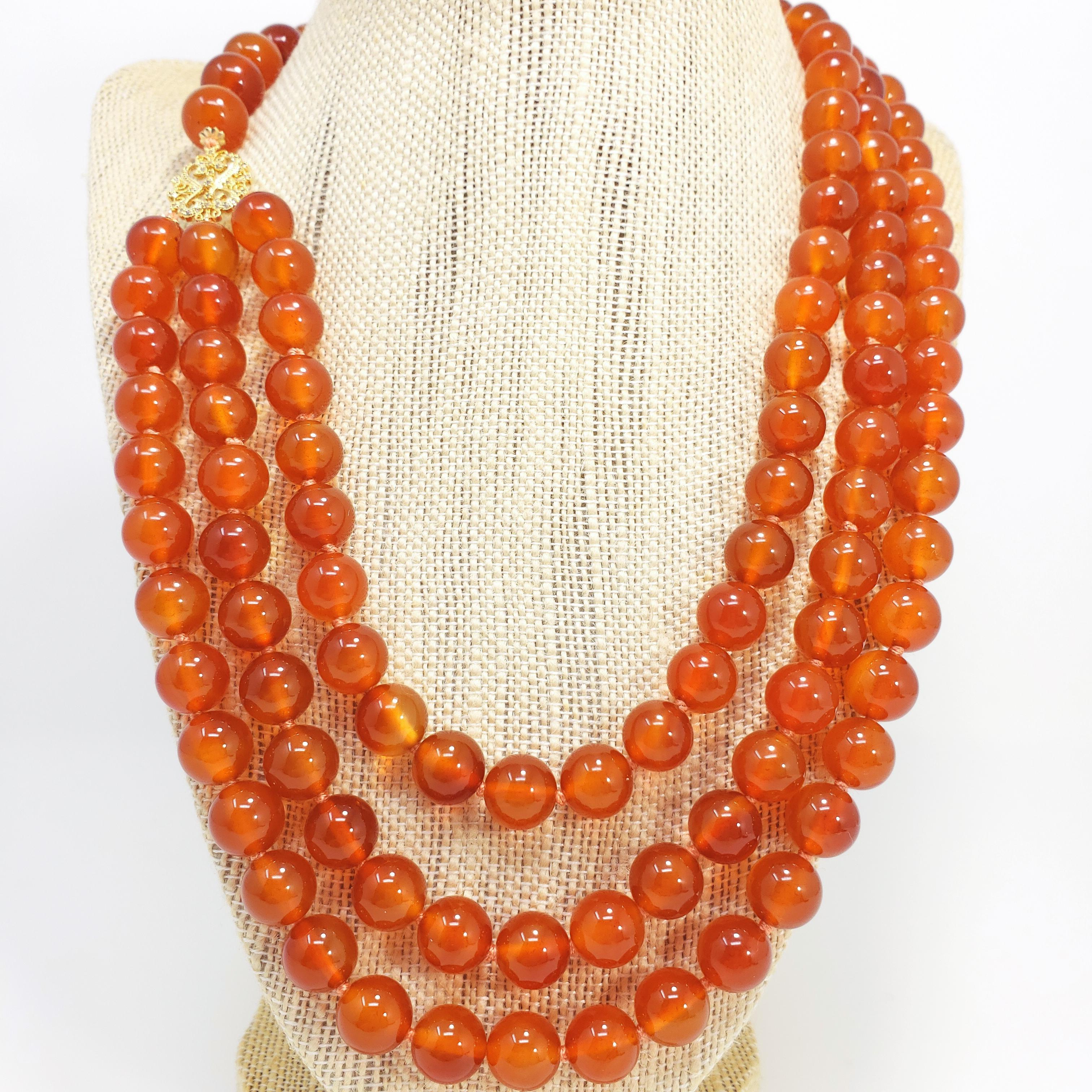 A bold and bright triple strand necklace! Features three strands of 10mm carnelian beads, connected to a single strand with a vermeil cubic zirconia-accented connector. The clasp itself features a 2.3cm carnelian cabochon, bezel-set in a round,