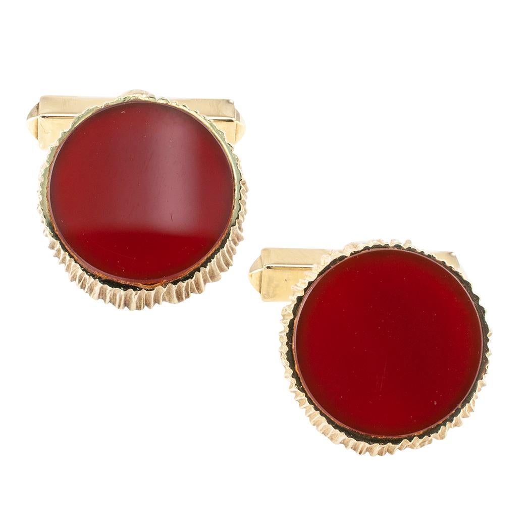 1970s carnelian and gold cufflinks. Featuring a pair of flat buff-top, circular carnelian set in conforming, textured bezels to the articulated connectors, mounted in 14-karat yellow gold. We love that thanks to the understated richness of the